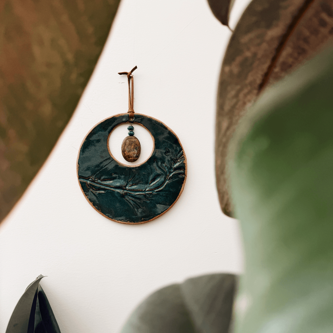 Handmade ceramic wall hanging with nature-inspired texture displayed on wall with rubber plant, made in the Santa Cruz Mountains California