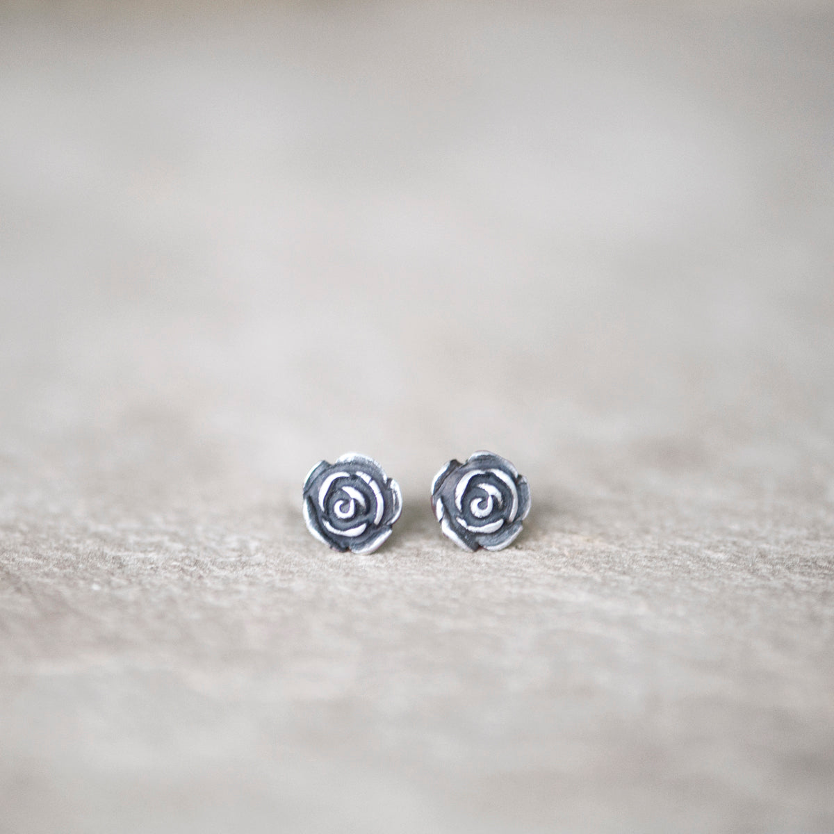 Handmade sterling silver rose stud earring on a white background.