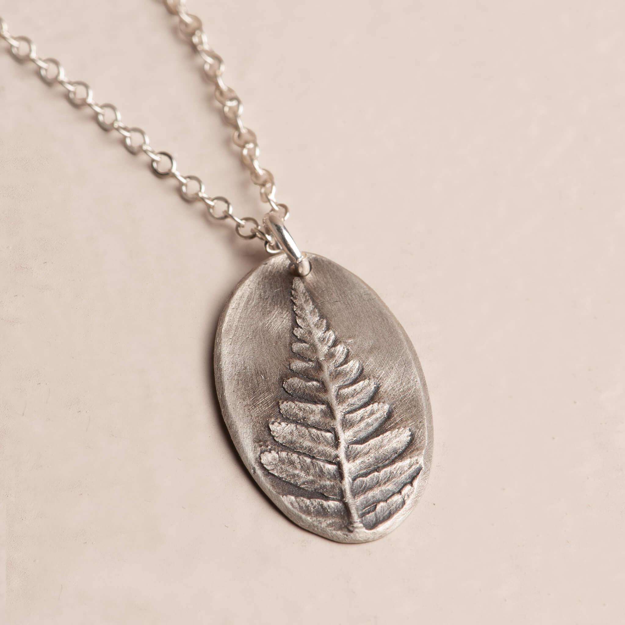 Close-up artisan sterling silver botanical fern impression pendant necklace, handcrafted jewelry, Jester Swink Santa Cruz Mountains