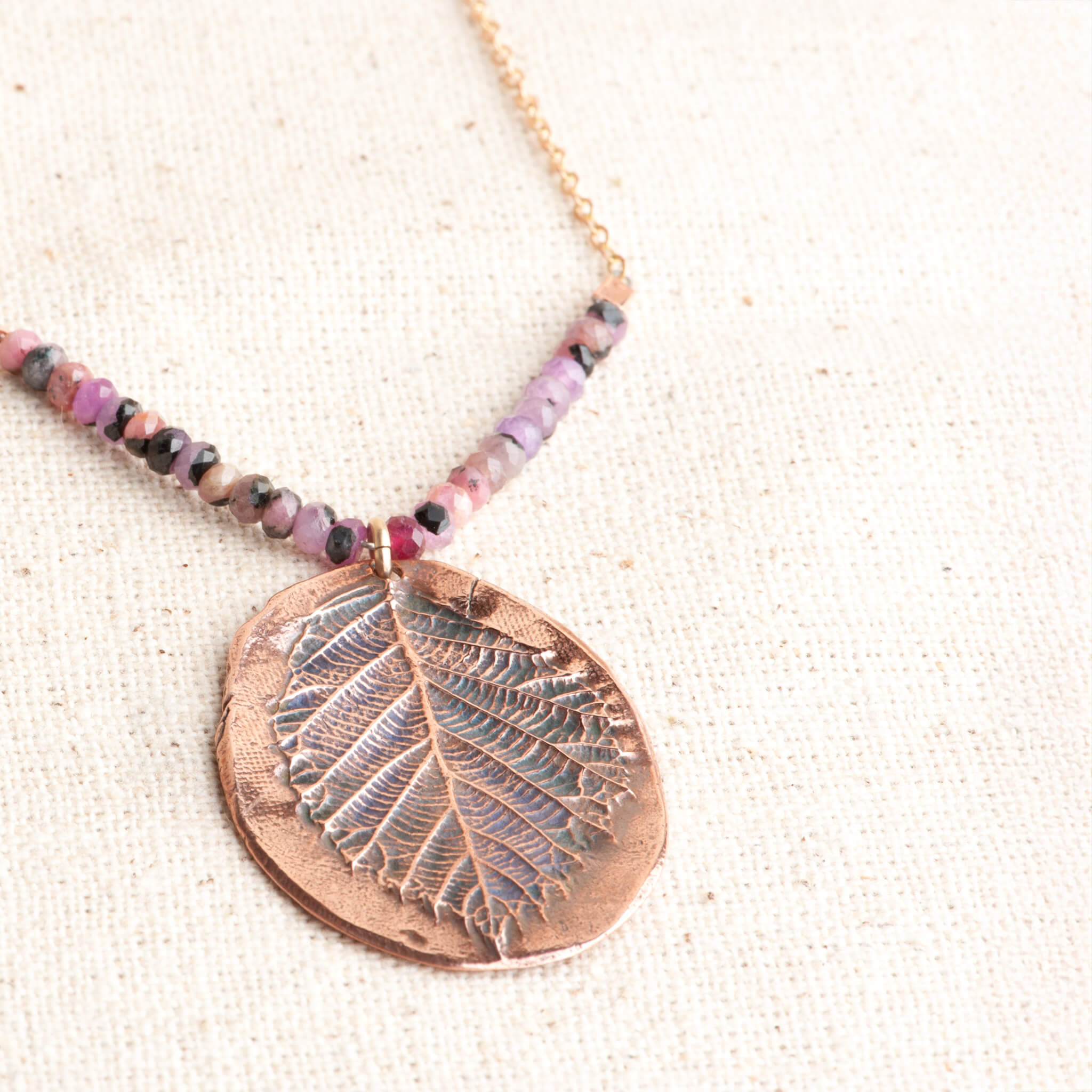 Close-up of unique copper blackberry leaf pendant texture and ruby gemstone