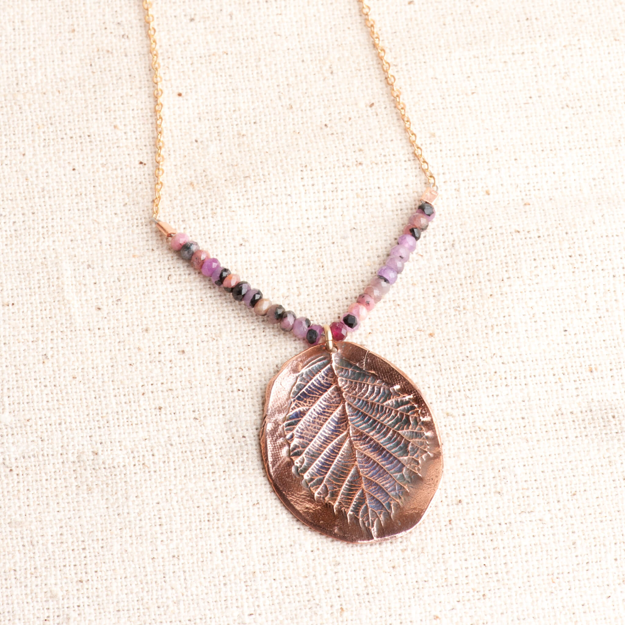 Close-up of unique copper blackberry leaf pendant all the texture and beautiful ruby gemstones