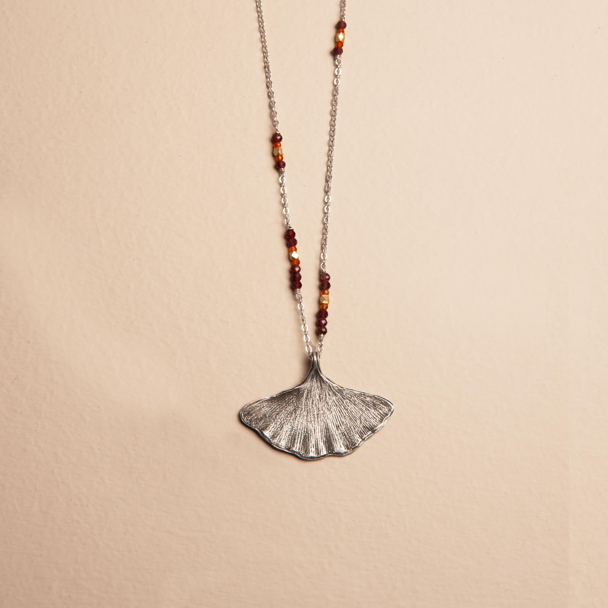 Asymmetrical sterling silver ginkgo leaf necklace with garnet, carnelian, and brass bead accents