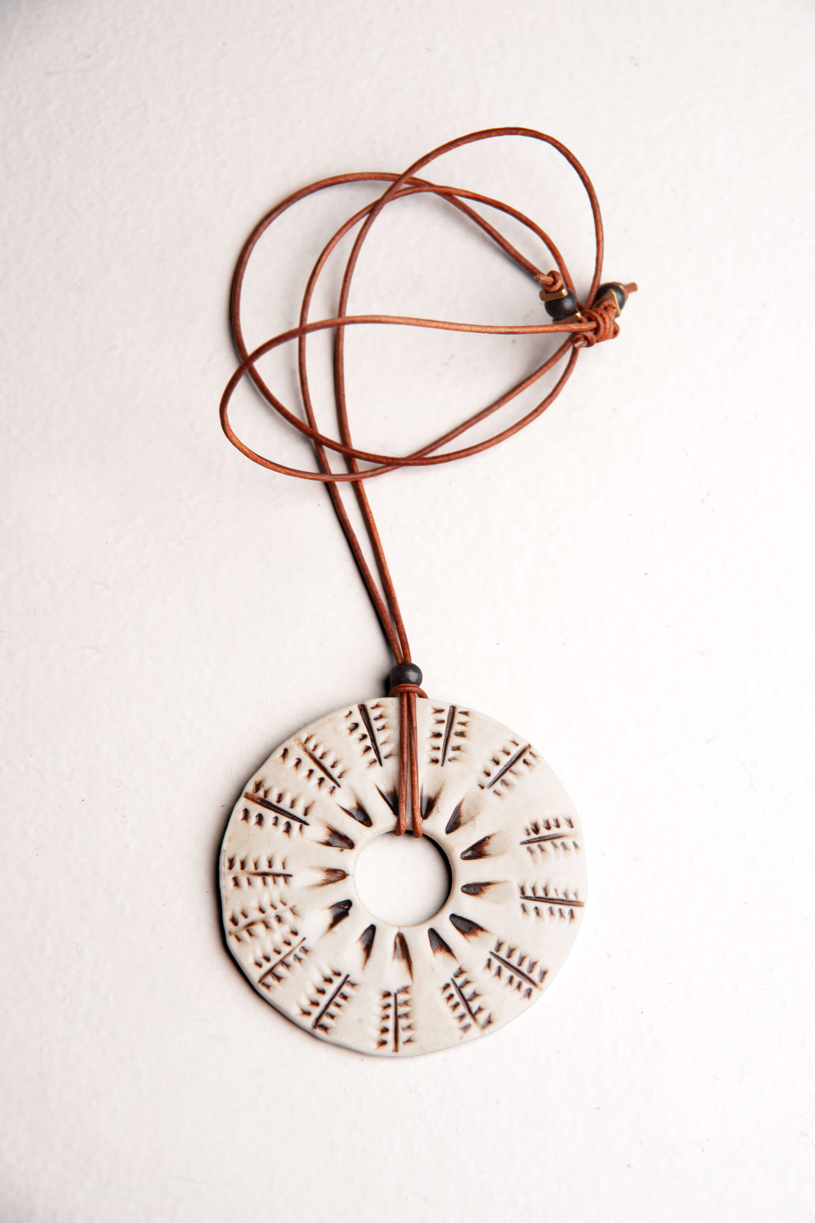 Handmade ceramic botanical sunburst pendant necklace in ivory porcelain with brown underglaze on caramel Italian leather, kiln fired by Jester Swink Santa Cruz Mountains — From the Fire FTF_0726