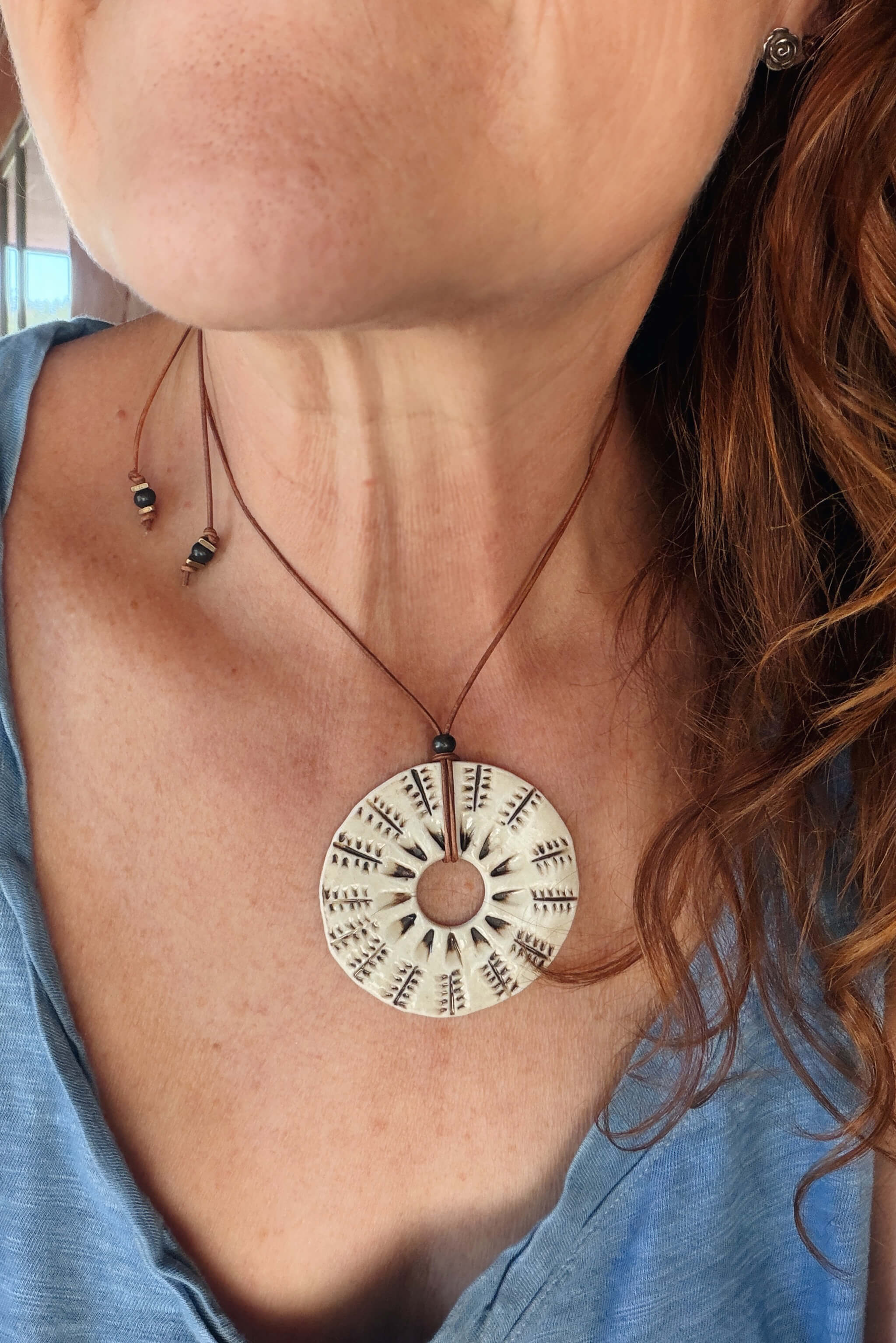 Handmade ceramic botanical sunburst pendant necklace worn at shorter length — botanical ceramic jewelry From the Fire FTF_0726 by Jester Swink