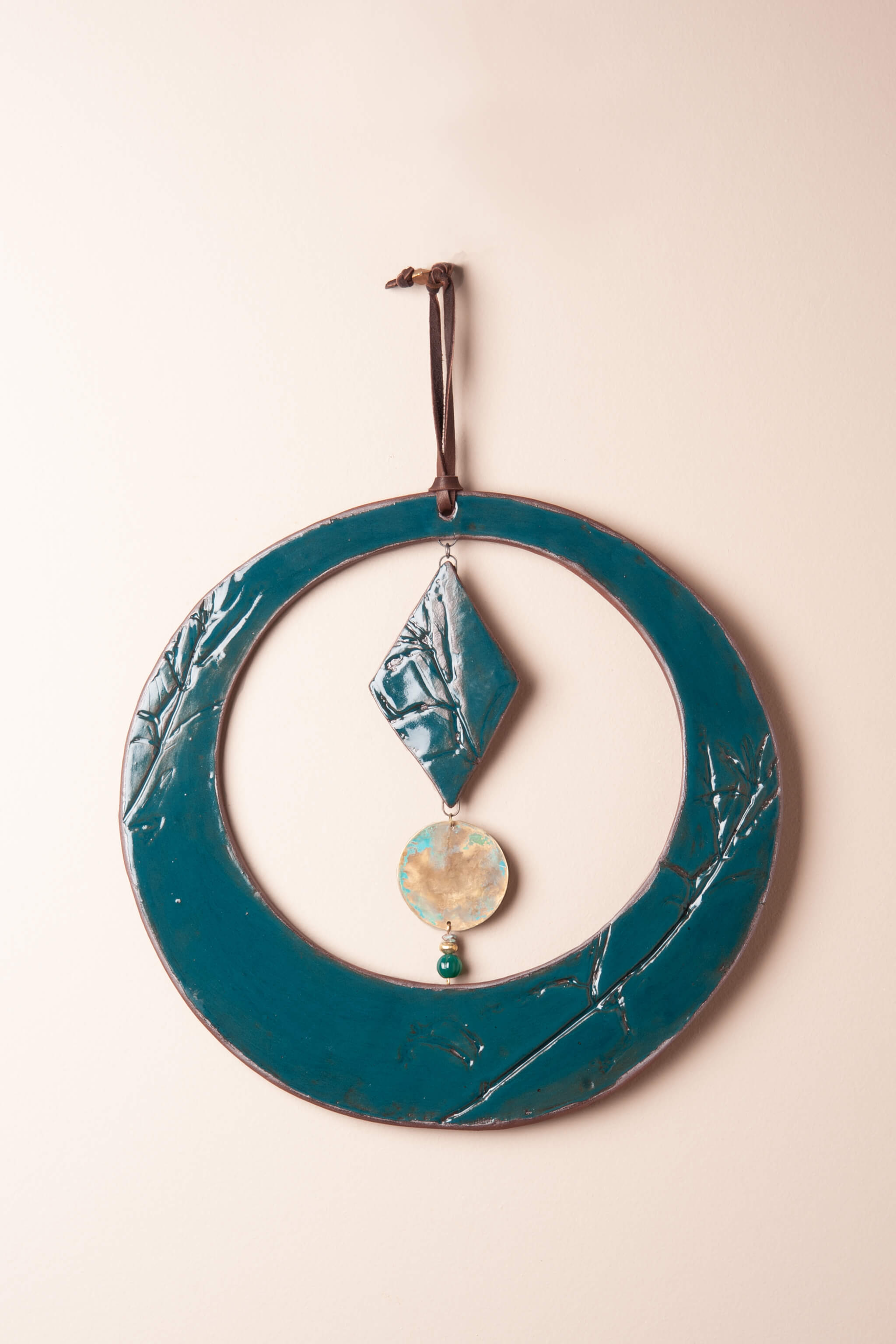 Handmade round wall hanging in deep teal glaze with green onyx and brass disc — kiln fired by Jester Swink, Santa Cruz Mountains