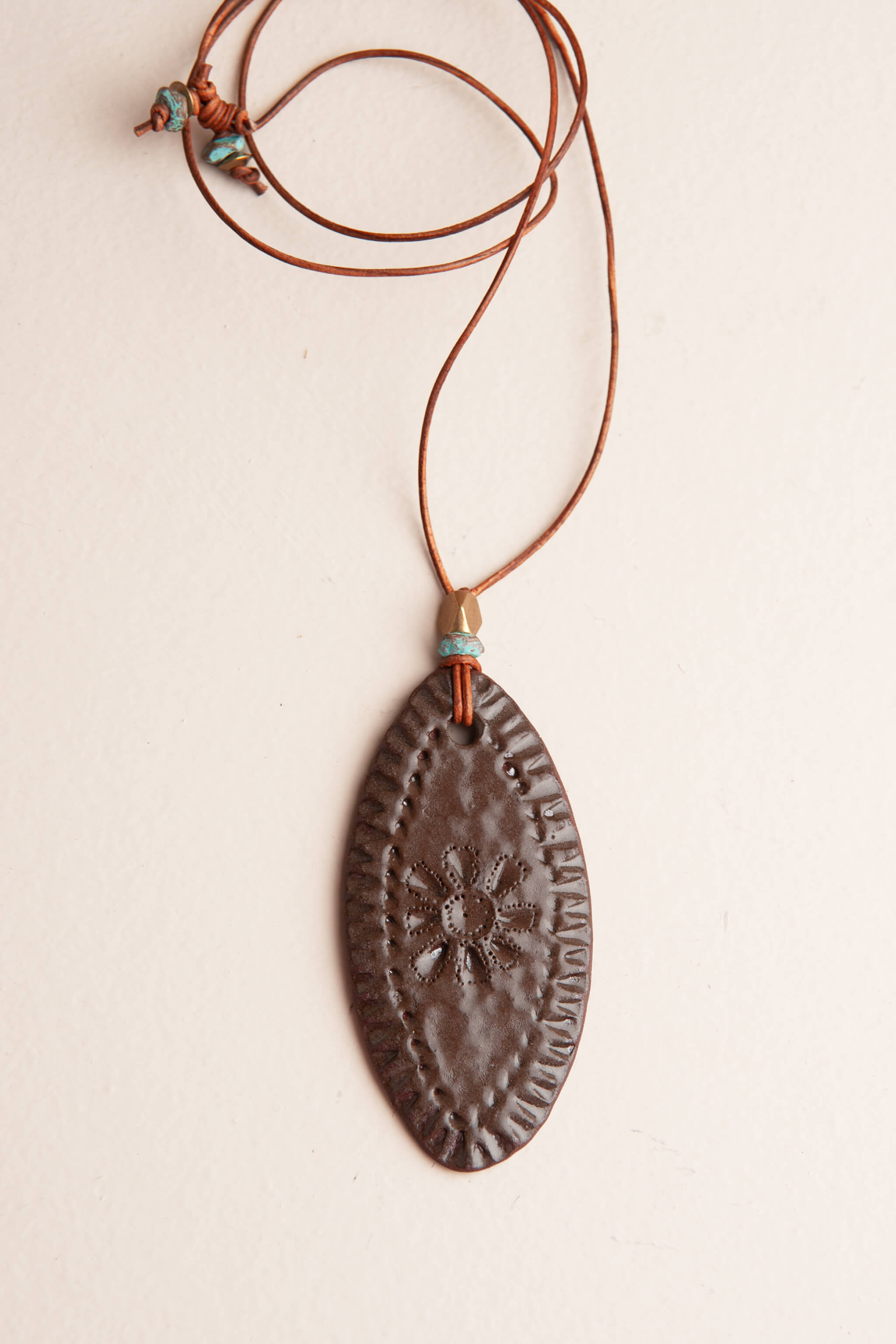 Handmade chocolate terracotta ceramic oval pendant necklace with hand pressed desert bloom and patina brass on Italian leather, kiln fired by Jester Swink Santa Cruz Mountains — From the Fire FTF_0726