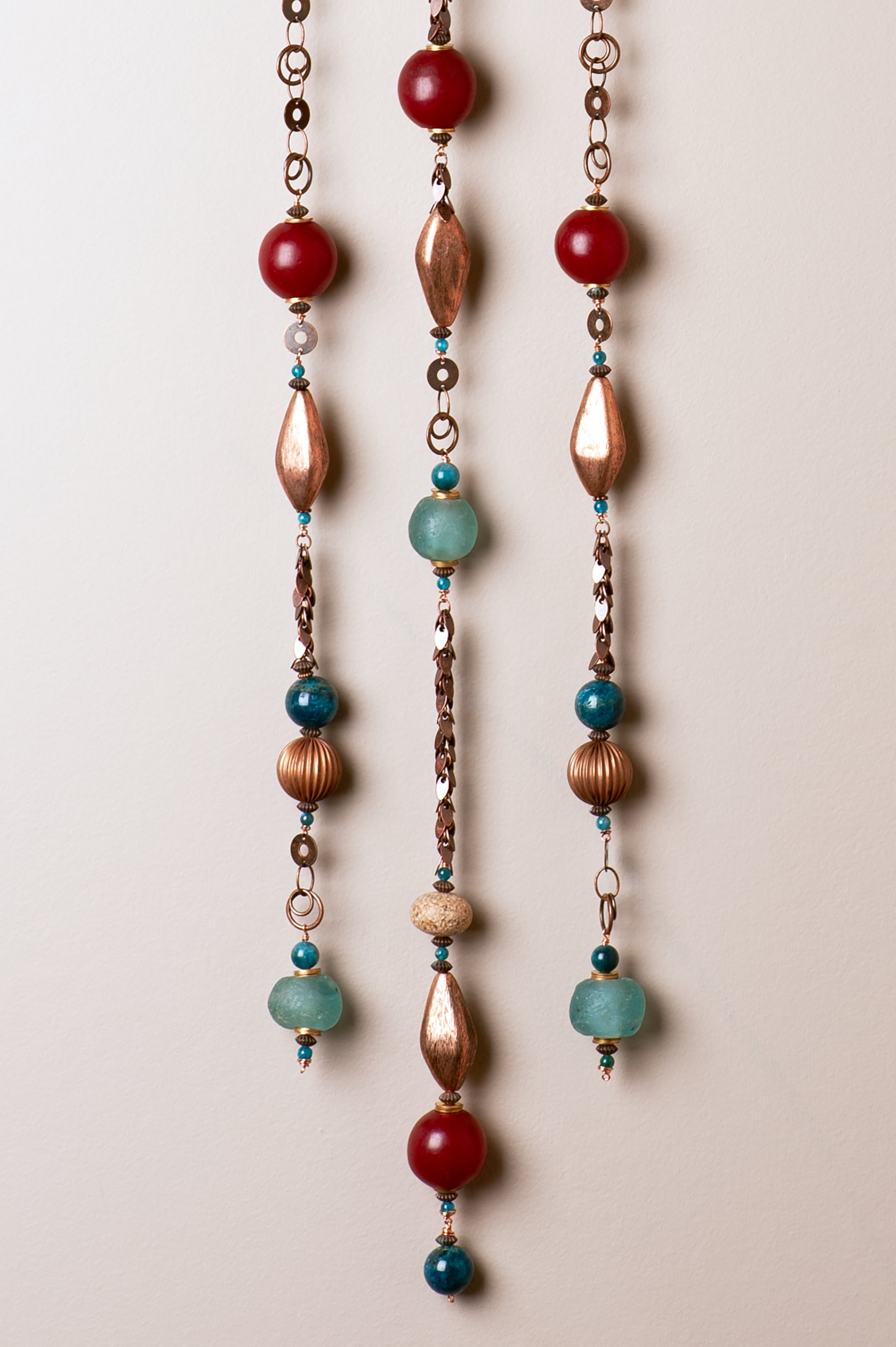 Close-up detail of handcrafted ceramic wall hanging showing carved Arizona sun rays, redwood needle impressions, and Southwest-colored beads including turquoise apatite and copper