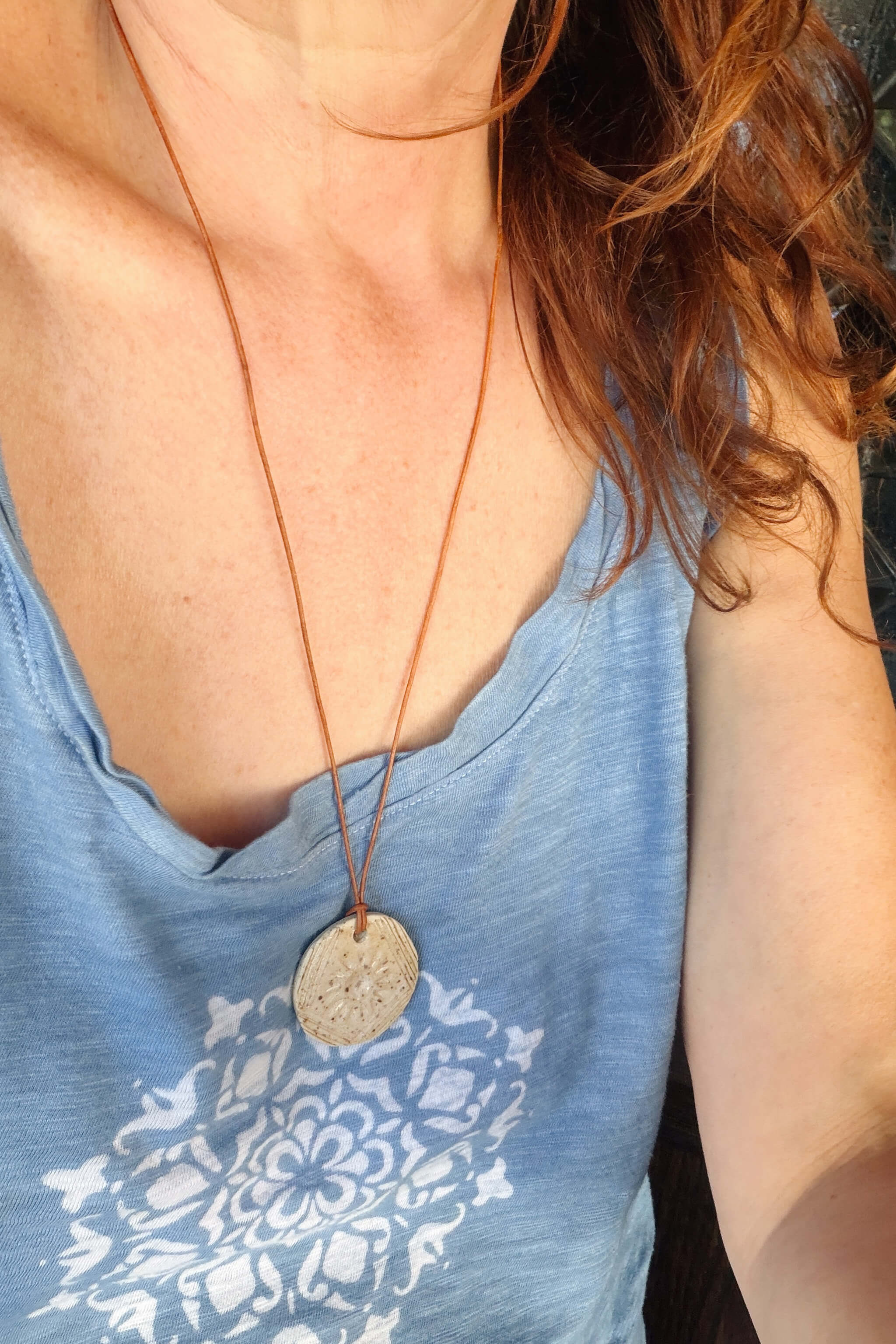 Handmade speckled white ceramic sunburst pendant necklace worn at long boho length on caramel leather — From the Fire FTF_0726 by Jester Swink