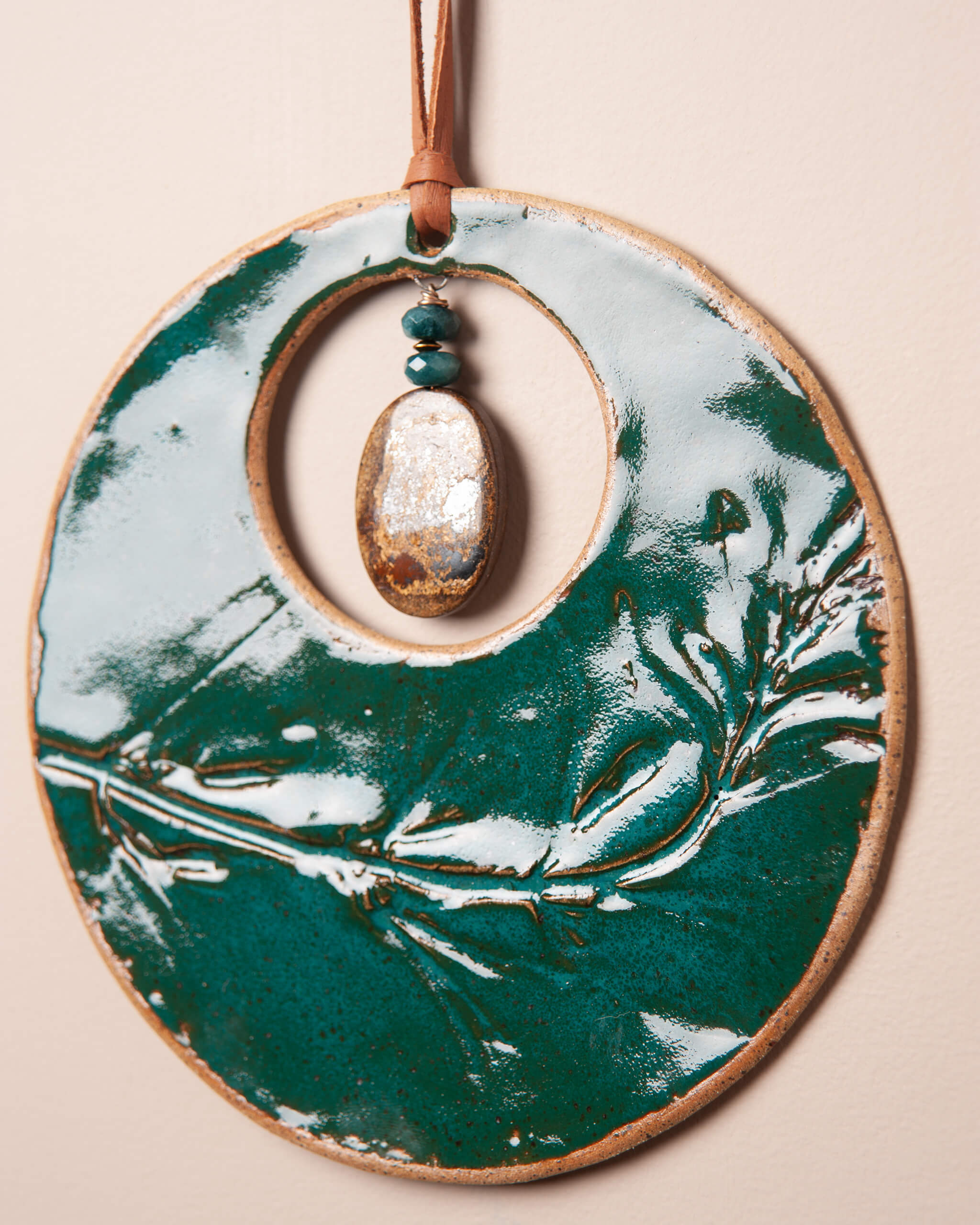 Close up of monkey flower impression in emerald glazed ceramic clay with bronzinite and green onyx pendant