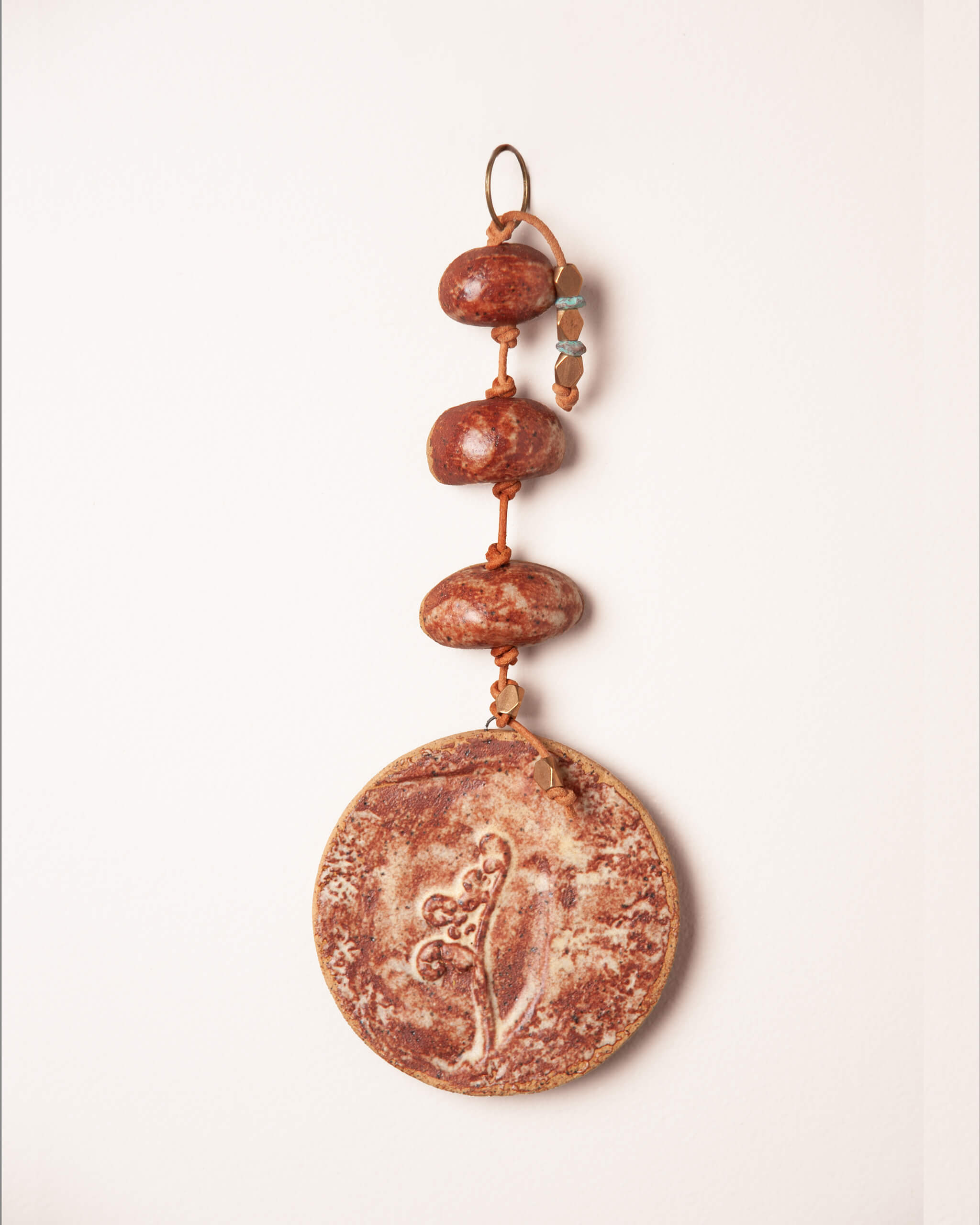 Hanging beautiful this fiddlehead fern impression on terracotta glazed ceramic disc with patinated brass and bronze accent beads