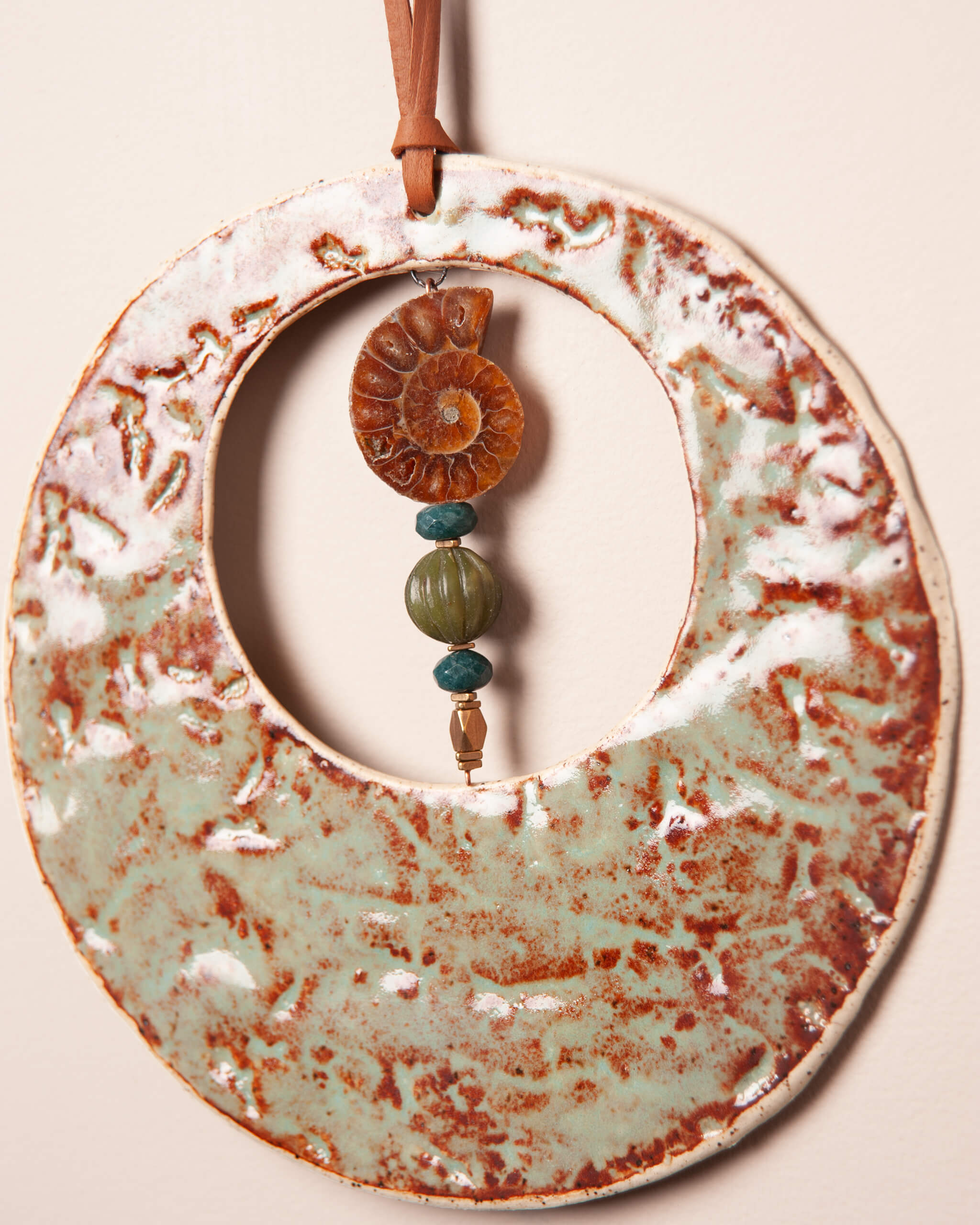 Close up of redwood bark impression in white speckled ceramic clay with real ammonite fossil and teal serpentine beads