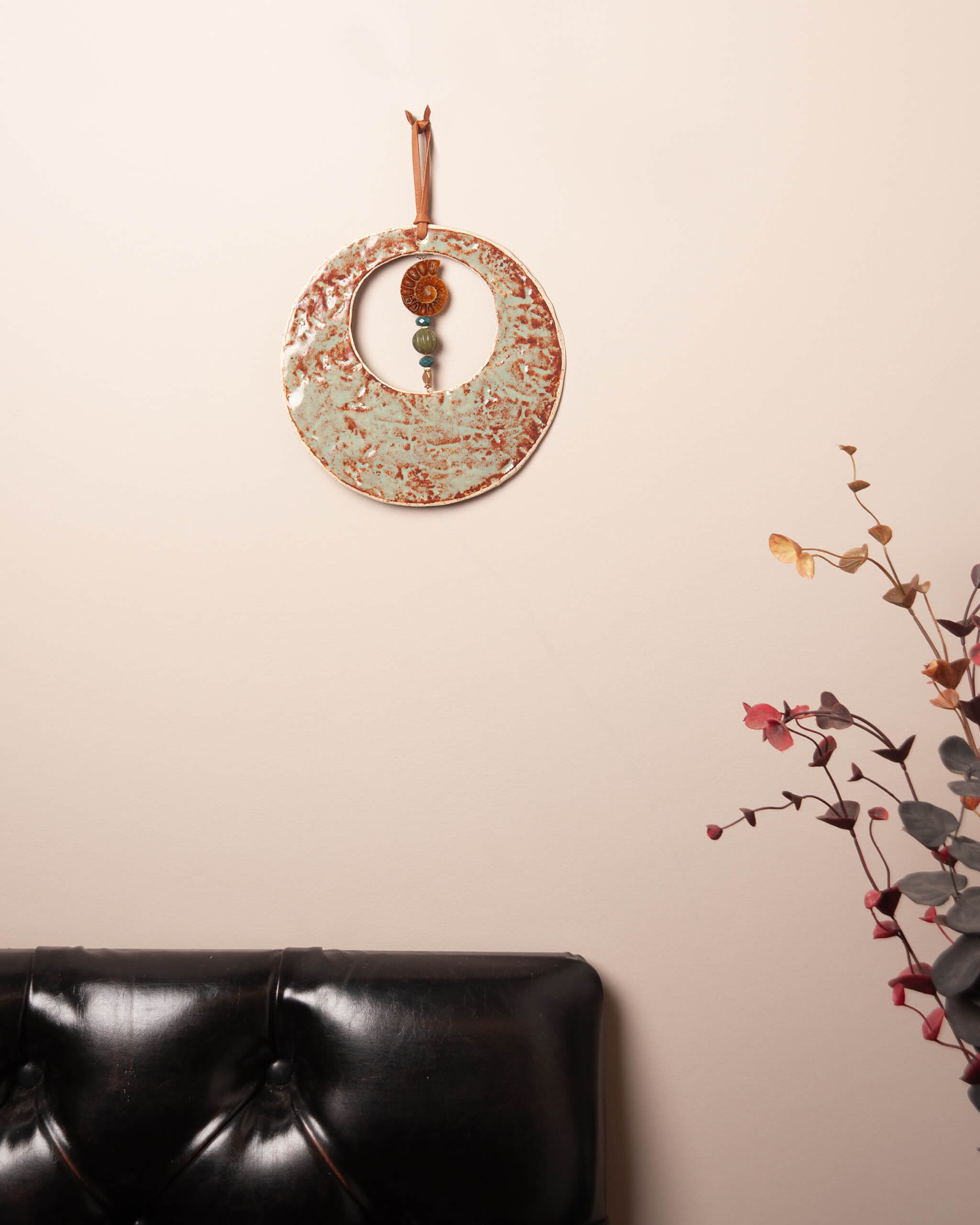 Fossil Moon handmade ceramic wall hanging in home setting showing sage and rust glaze detail