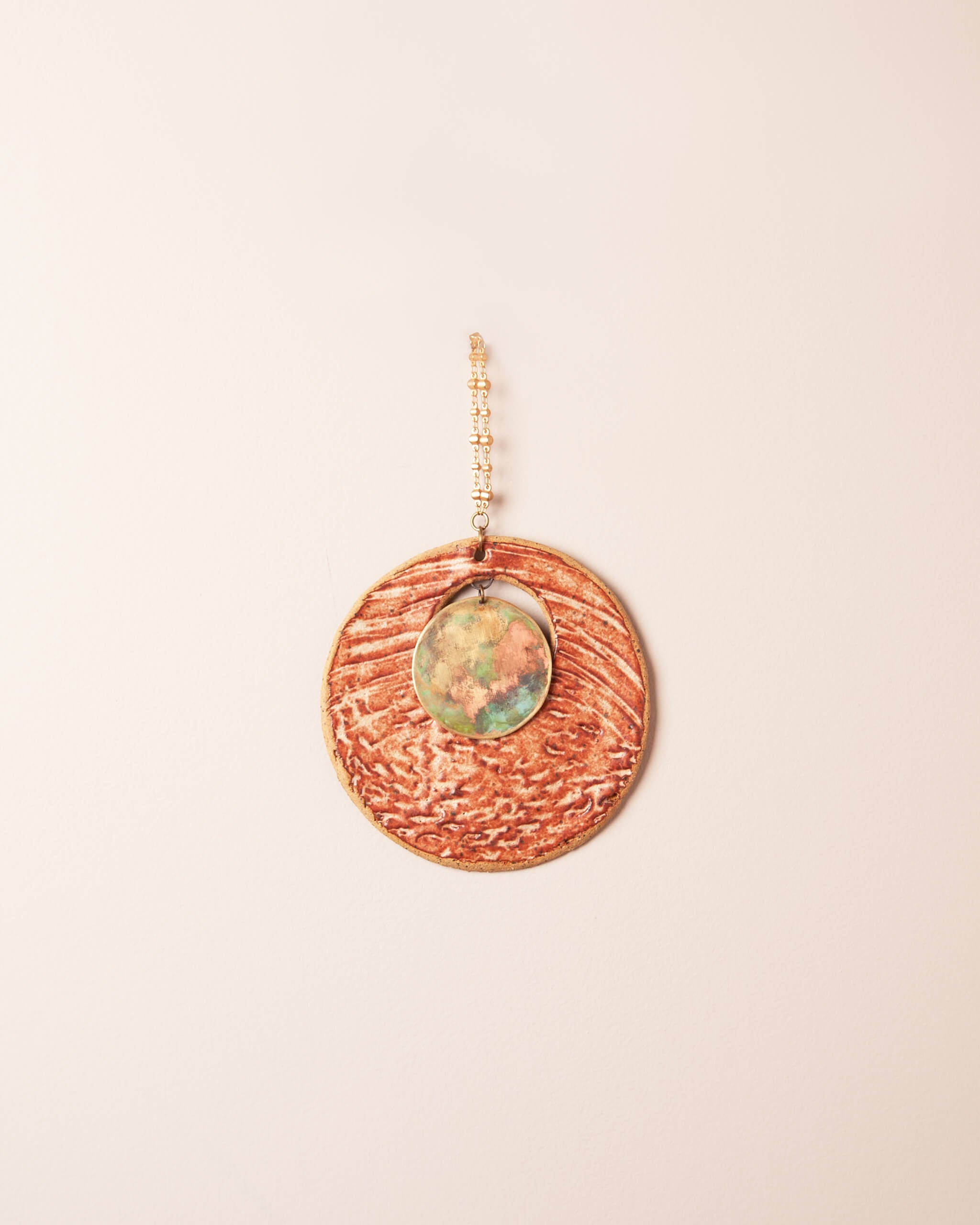 Patina Shore Moon small handmade ceramic wall hanging with shell and pinecone impressions, rusty cream glaze and hand patinated brass disc, made in the Santa Cruz Mountains of California