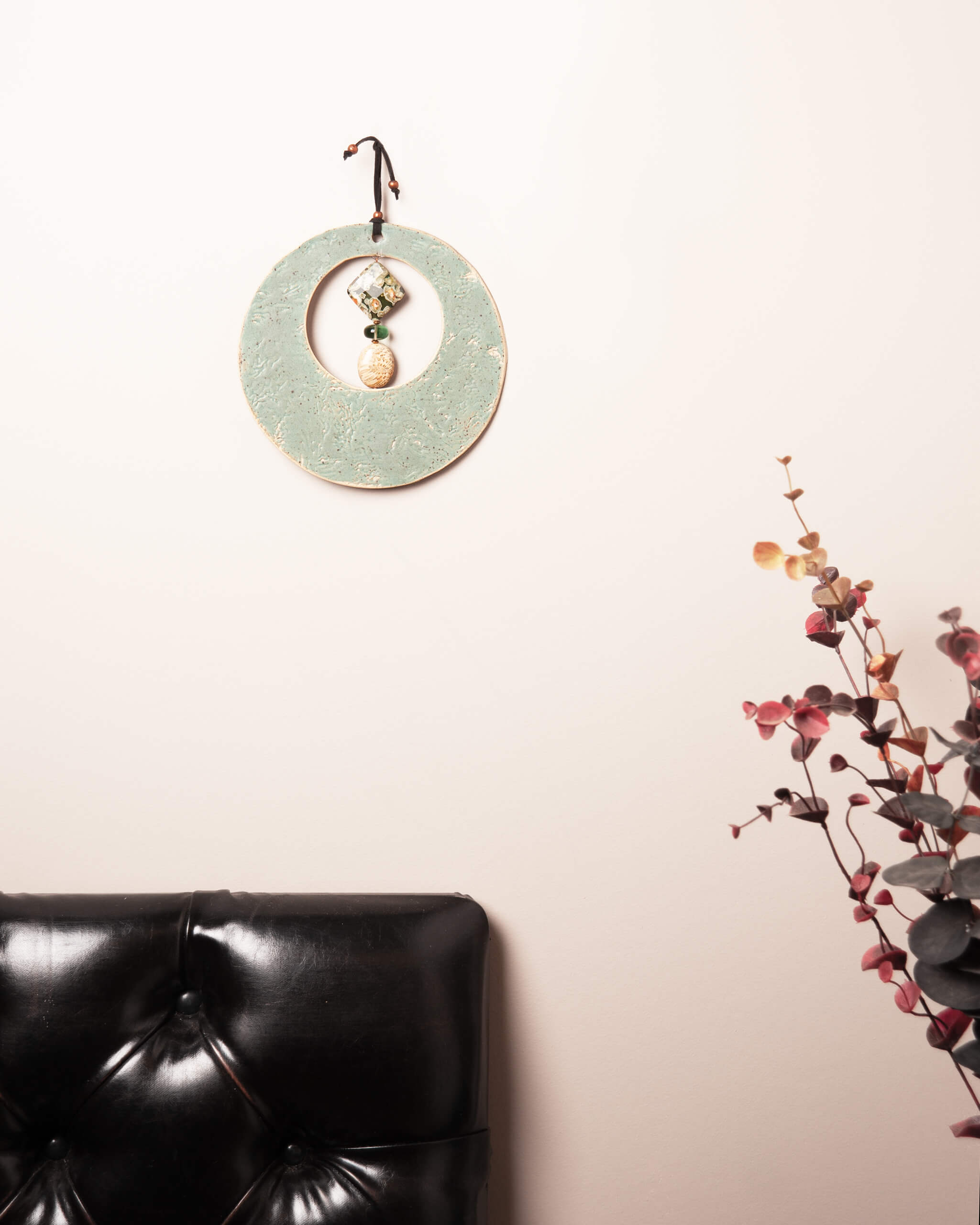 Sea Kelp Moon ceramic wall hanging displayed on blush wall showing full seafoam glaze and kelp texture detail