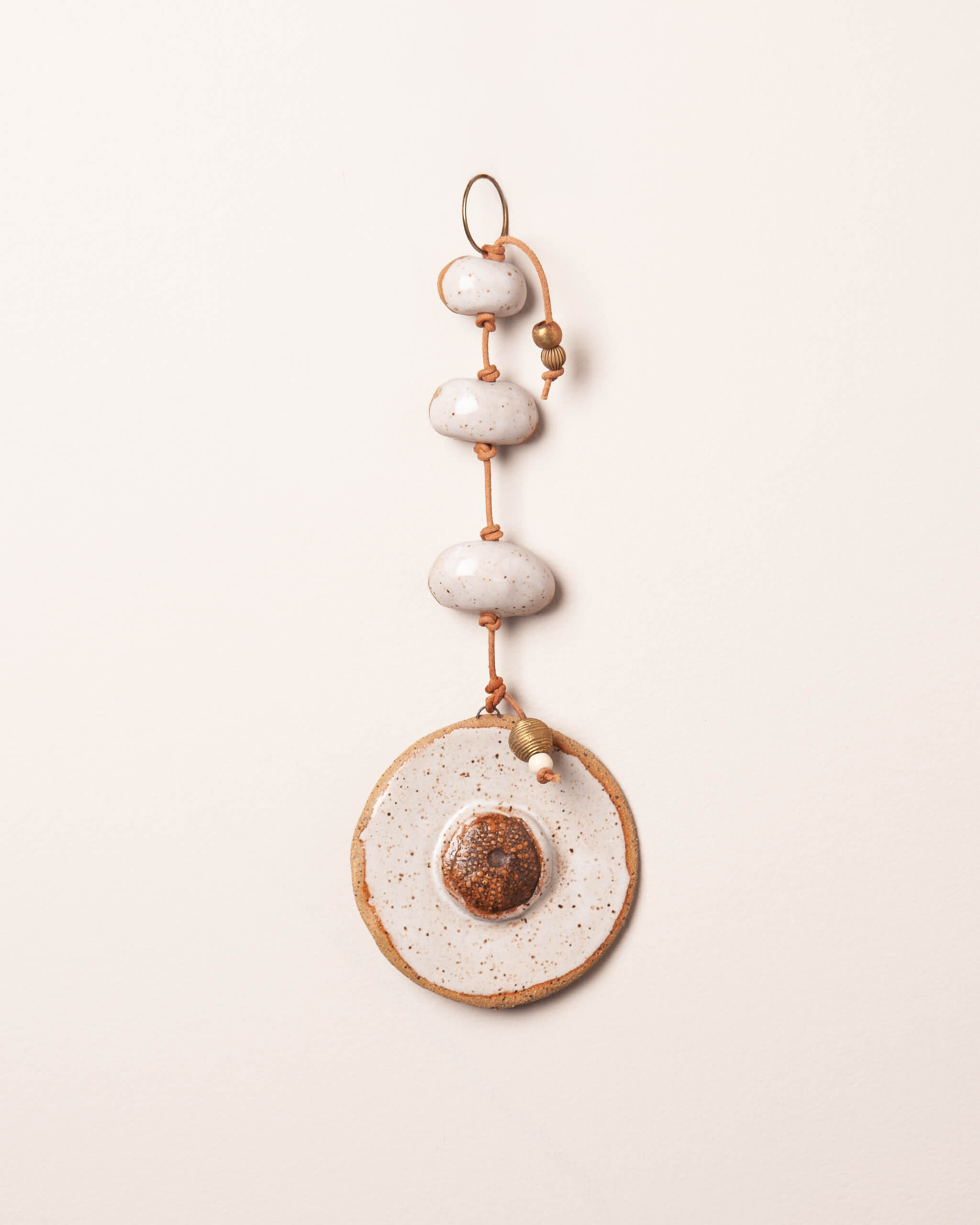 Sea Urchin Stack handmade ceramic wall hanging with river rock forms, white frost glaze and Moroccan fossil sea urchin impression, made in the Santa Cruz Mountains of California