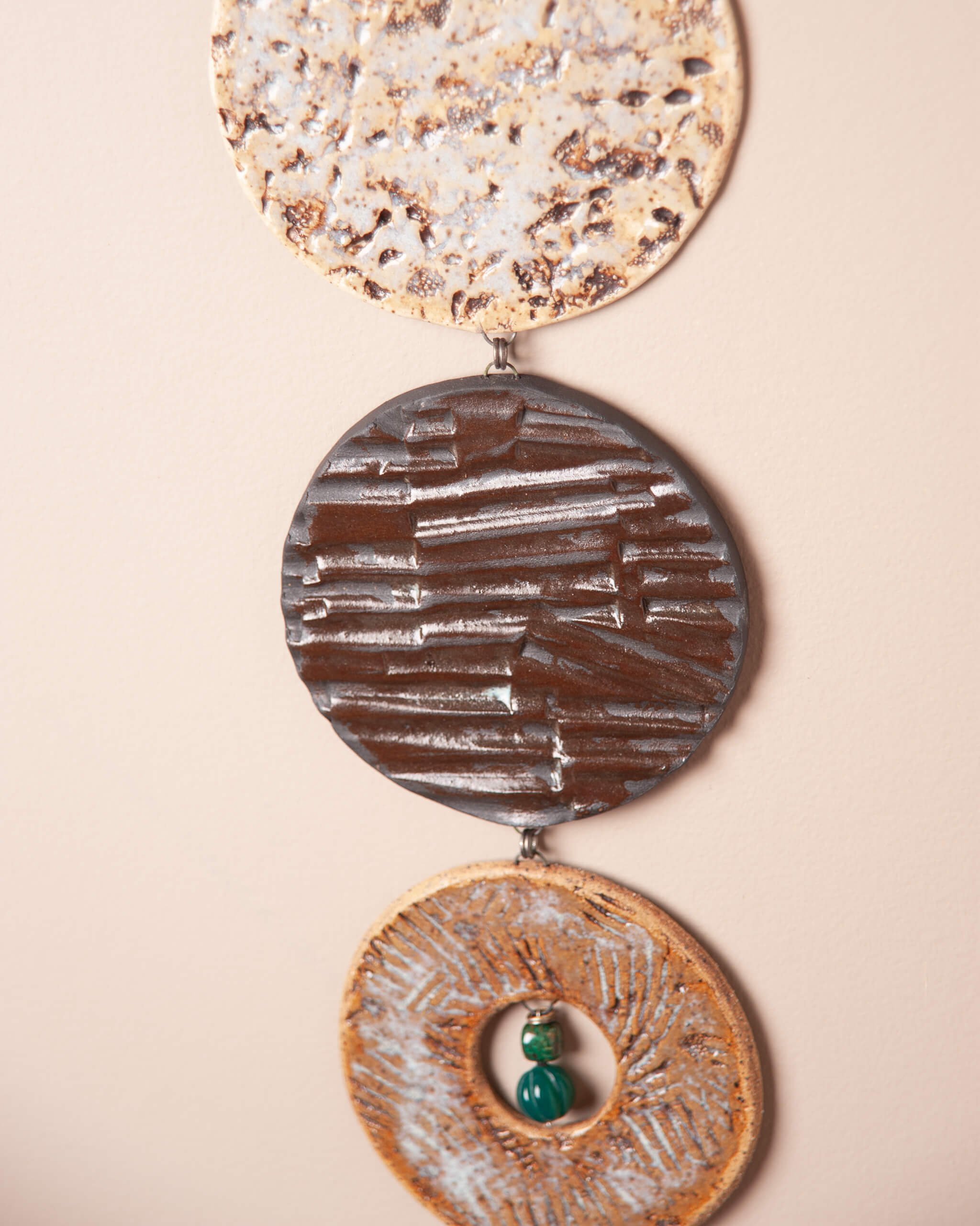 Close up of three ceramic discs showing white speckled abalone coral impression, dark night clay mountain rock texture and sandy river rock redwood needle impression with chrysocolla and green jade