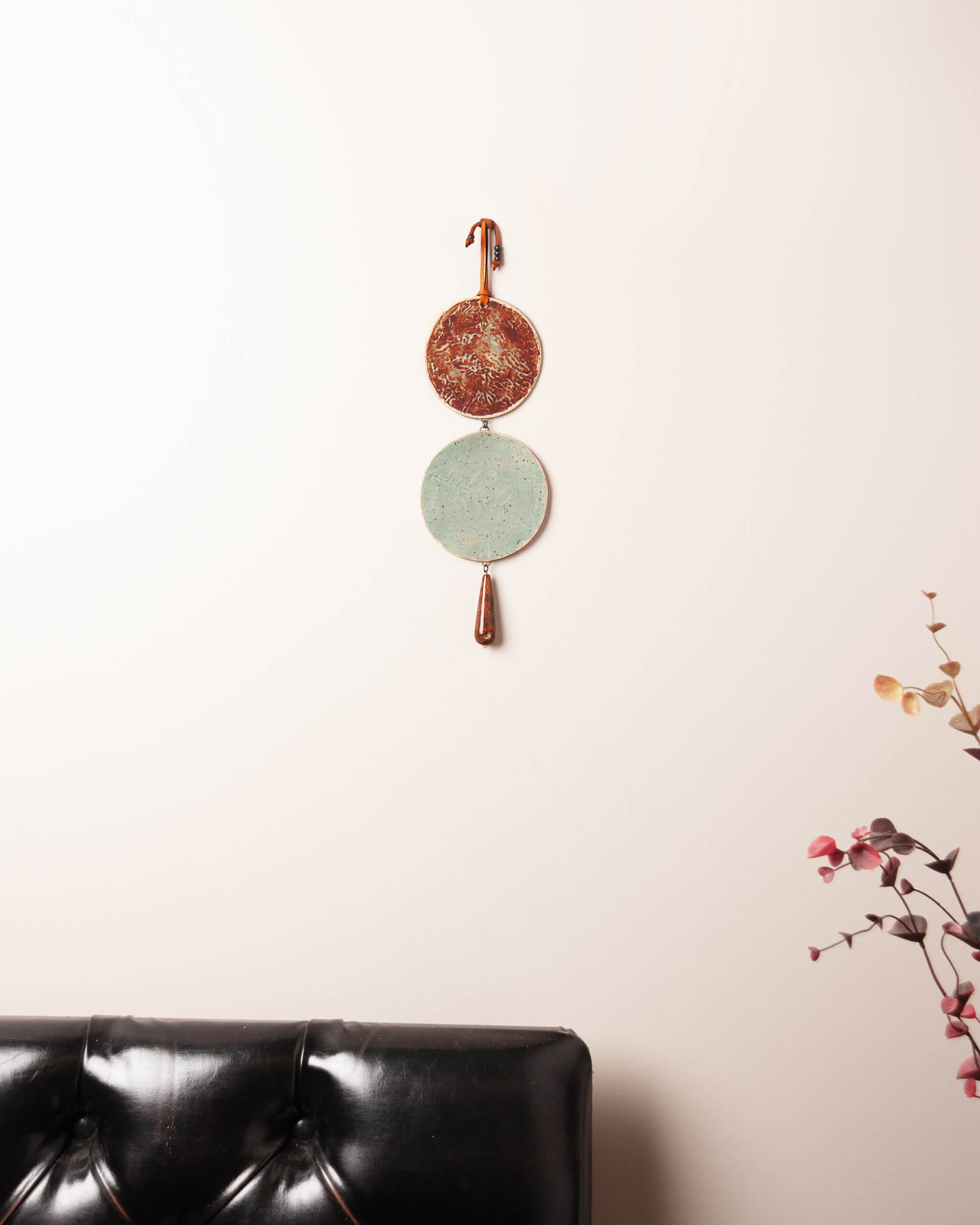 Tide and Fern Cascade ceramic wall hanging displayed in home setting showing full two disc cascade construction and contrasting glaze colors