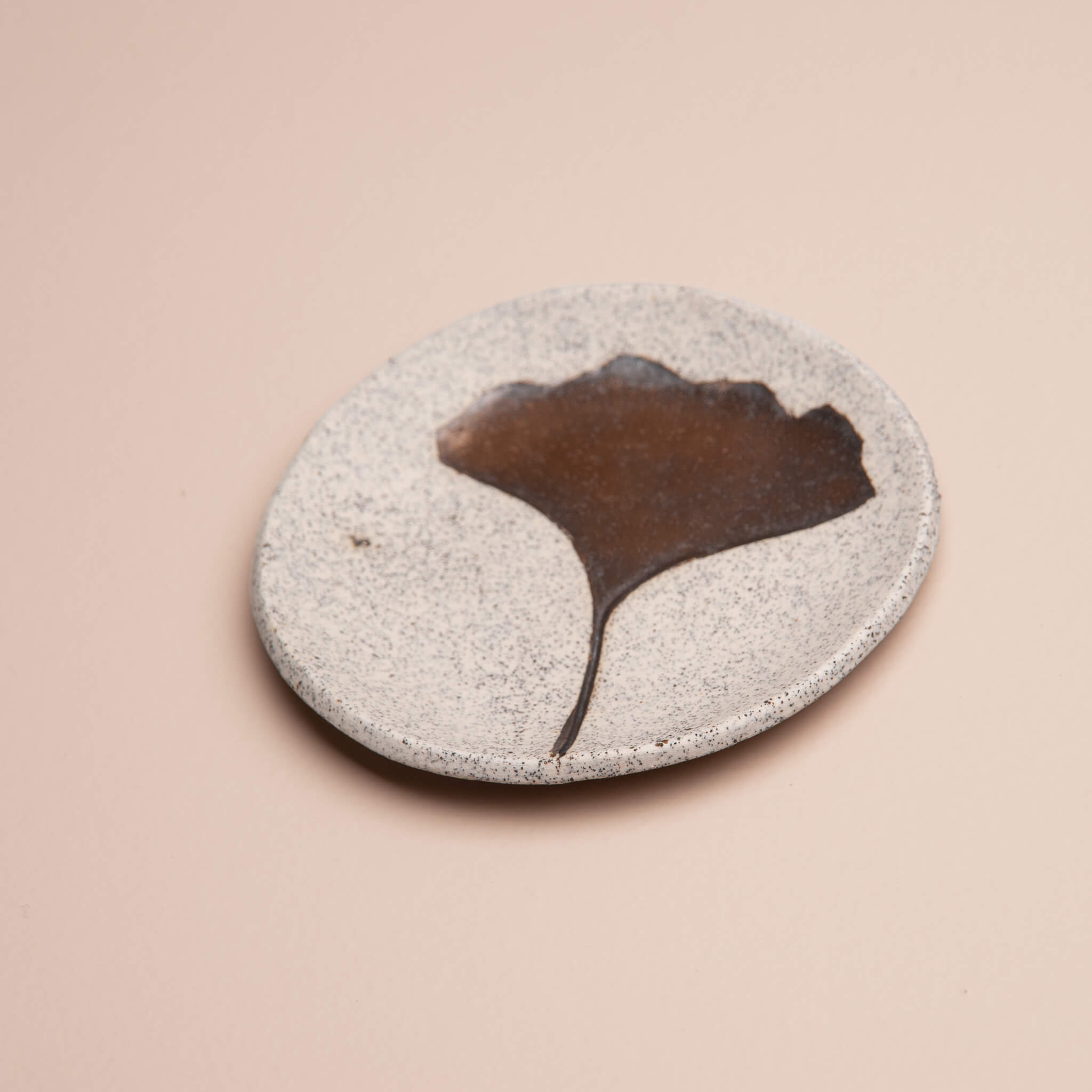 Angled view of handmade ceramic ginkgo ring dish with metallic gold glaze accent, showing its texture and depth, by Jester Swink