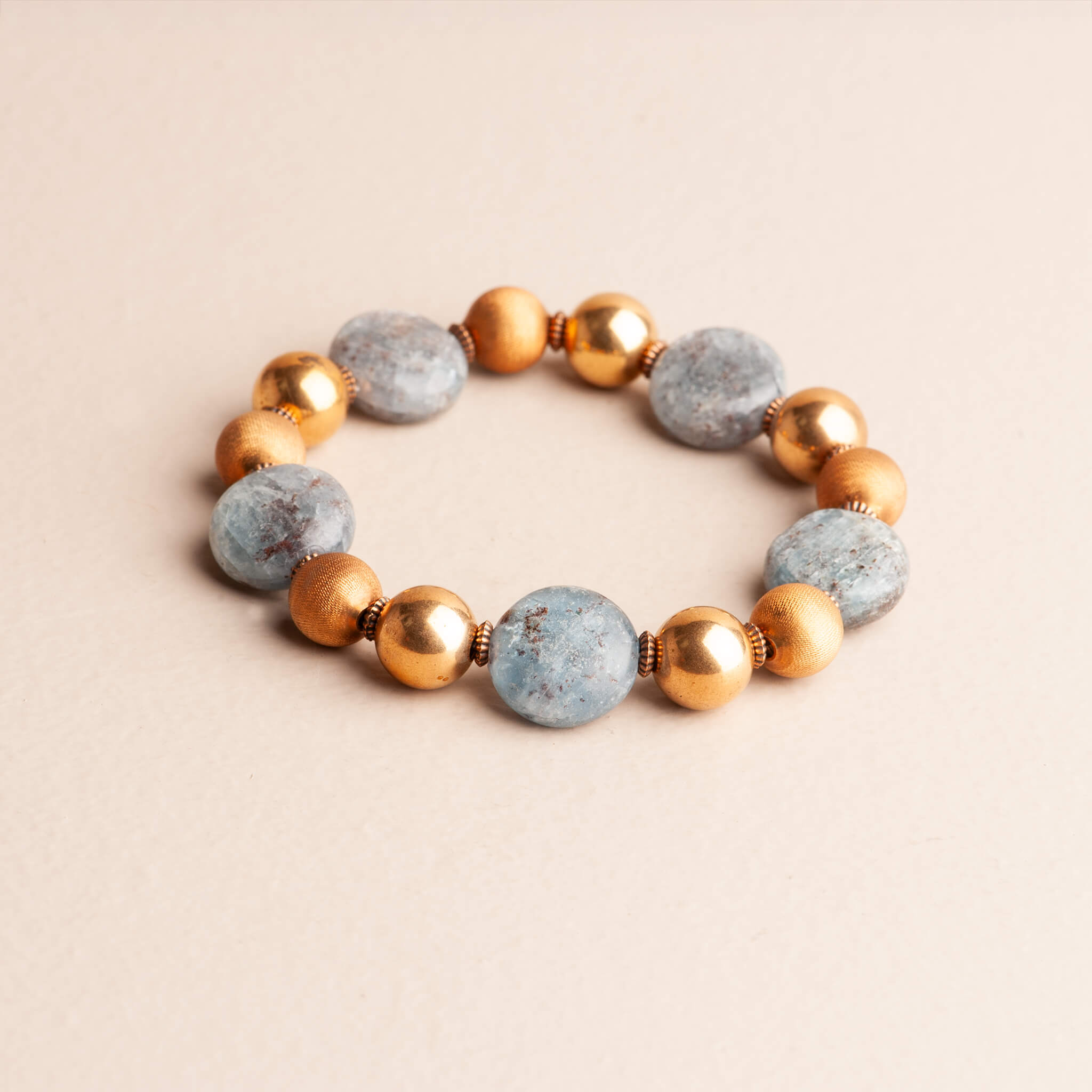 Handmade 7-inch statement stretch bracelet featuring round blue Kyanite beads with silver iridescence, separated by textured, round vintage brass beads.