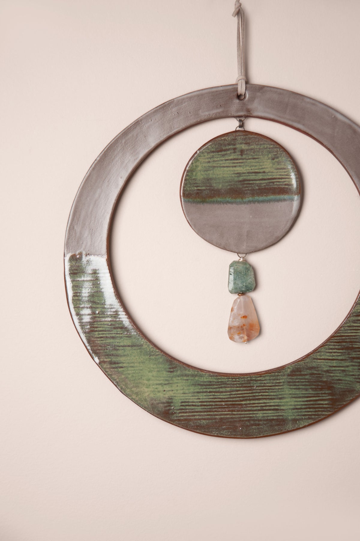 Detail of the modern stripes and stone dangle on a large handmade round ceramic wall hanging, kiln fired by Jester Swink, Santa Cruz Mountains California