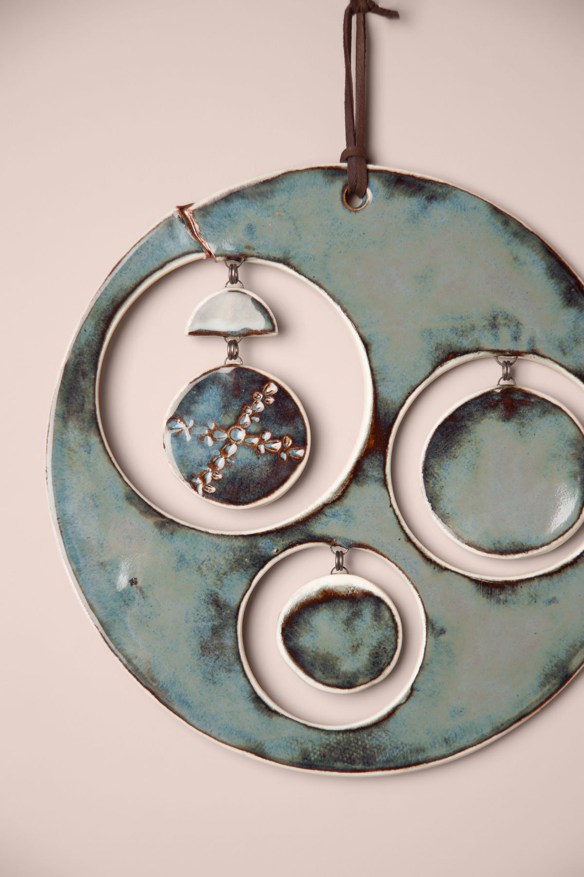 Detail of the hanging moon phases on a large handmade round ceramic wall hanging, kiln fired by Jester Swink, Santa Cruz Mountains California