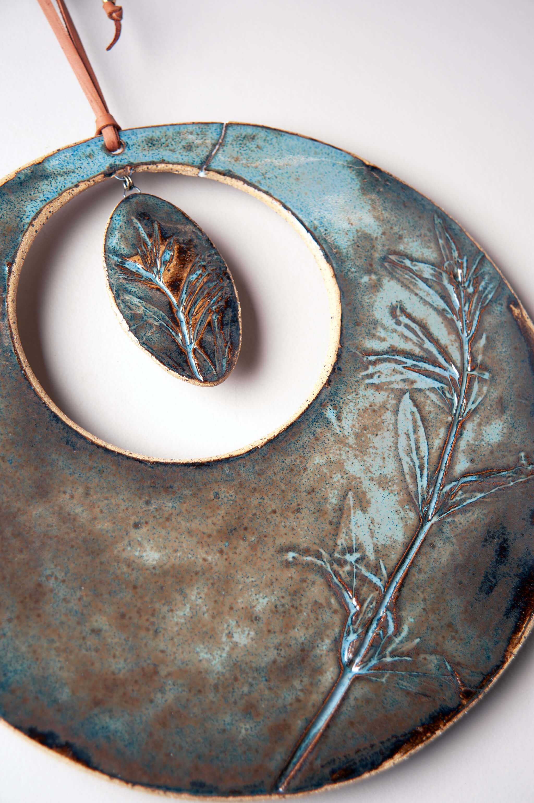 Oval ceramic element with monkey flower impression suspended inside large handmade ceramic wall hanging — From the Fire FTF_0726 by Jester Swink