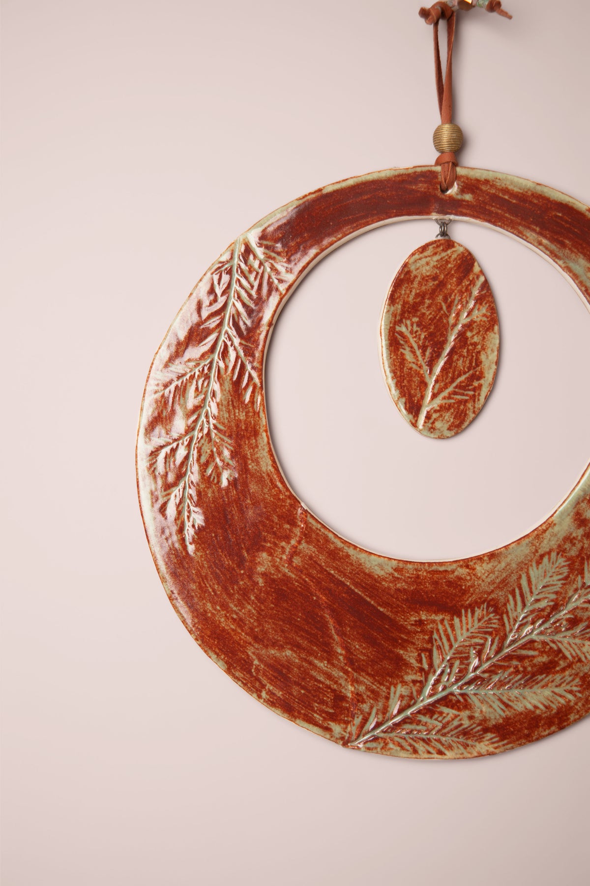 Detail of the pressed redwood needle impressions on a large handmade round ceramic wall hanging, kiln fired by Jester Swink, Santa Cruz Mountains California