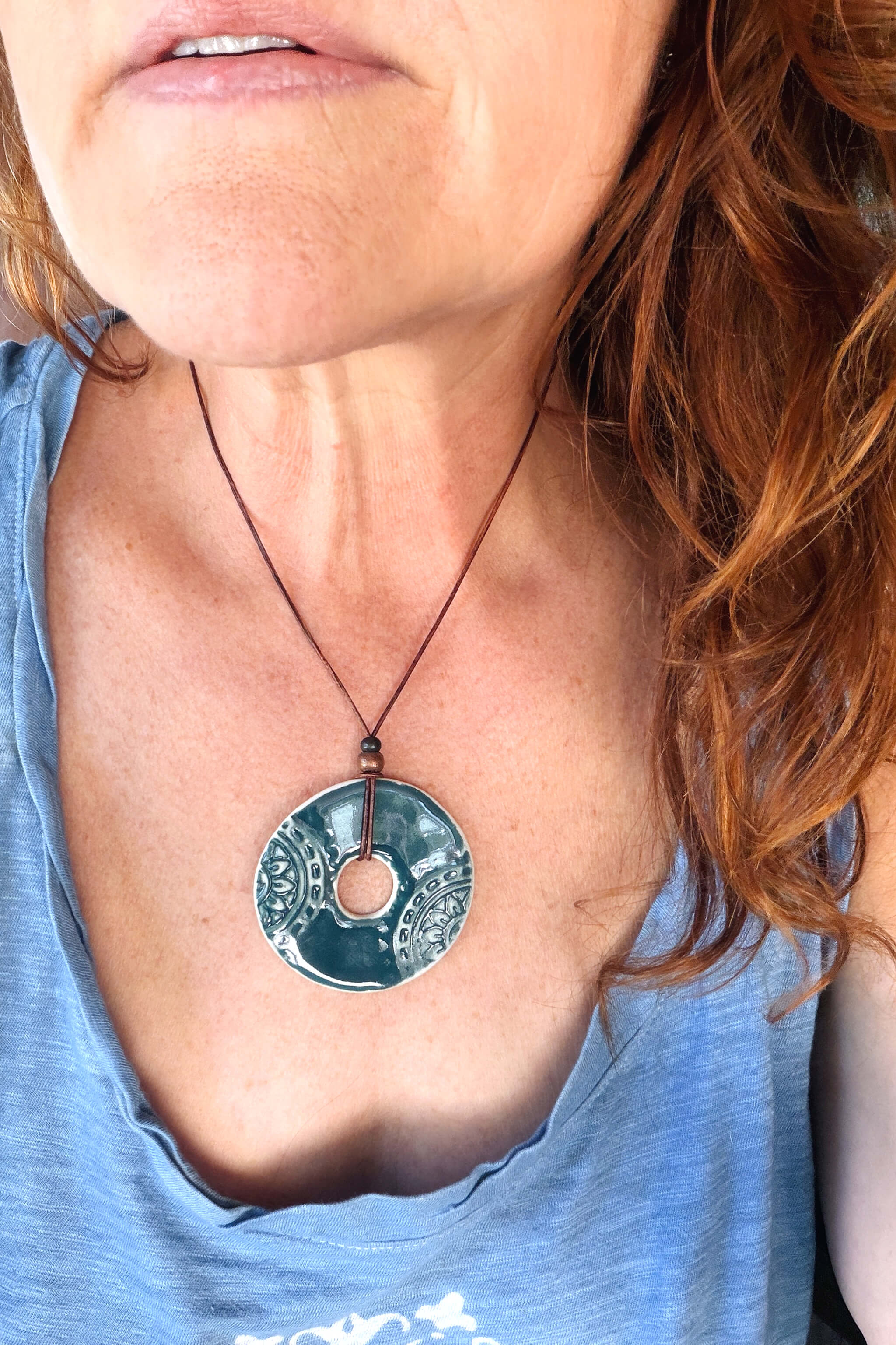 Handmade teal ceramic mandala pendant necklace worn at shorter length — mandala jewelry From the Fire FTF_0726 by Jester Swink