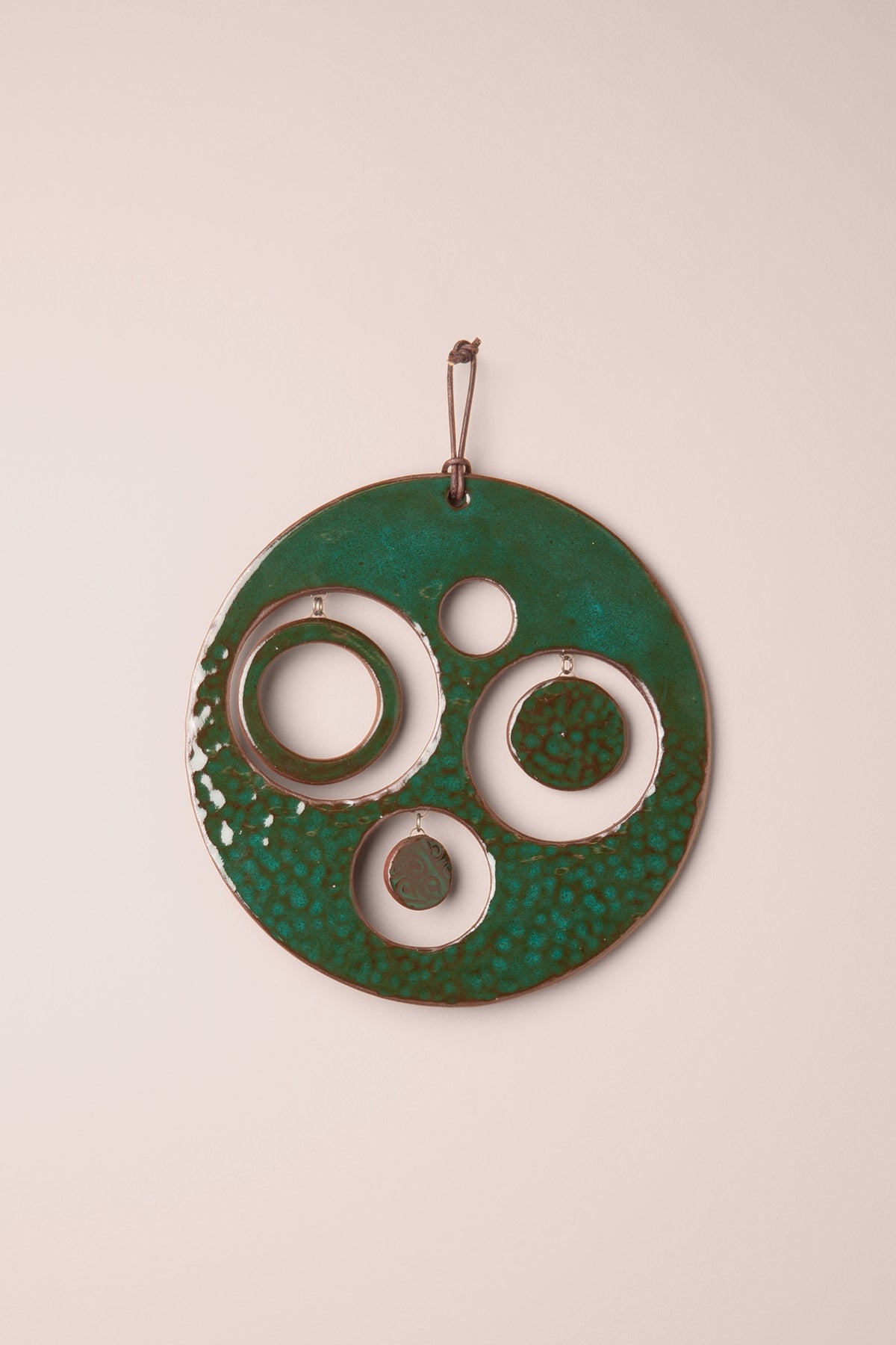 Medium handmade circle ceramic wall hanging in electric Emerald glaze with a hammered texture and four round windows, three holding small hanging moons, kiln fired by Jester Swink Santa Cruz Mountains — From the Fire FTF_1026