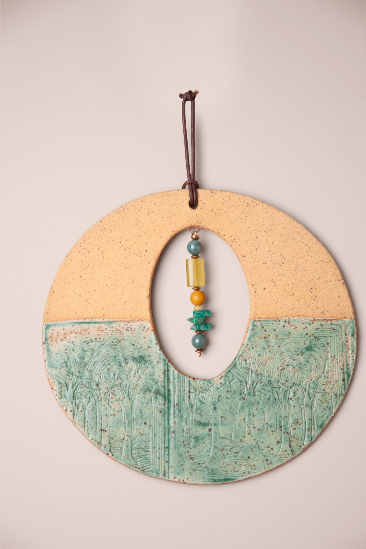 Detail of the stone stack in the oval window of a medium handmade round ceramic wall hanging with swirling tree texture, kiln fired by Jester Swink, Santa Cruz Mountains California