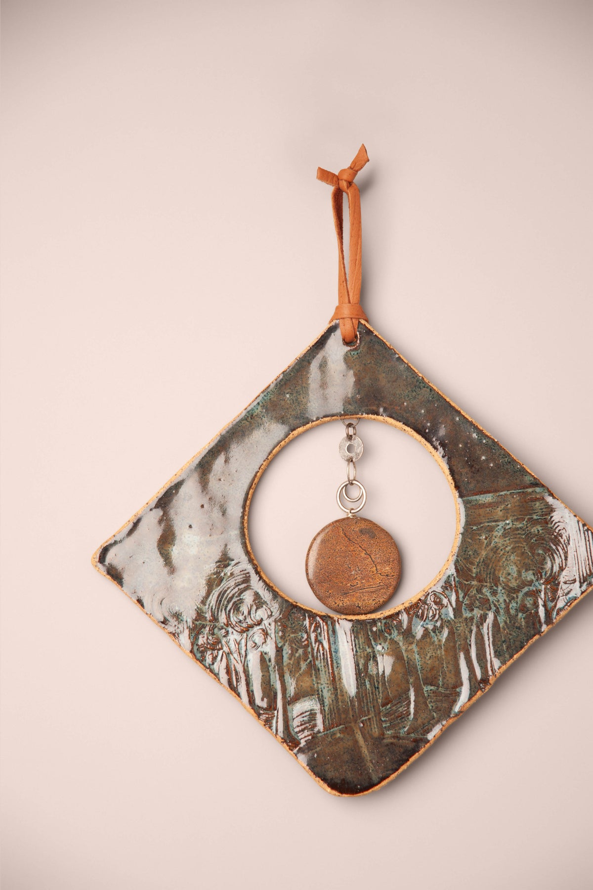 Detail of the rippled green glaze, swirling tree texture and picture jasper stone on a medium handmade diamond ceramic wall hanging, kiln fired by Jester Swink, Santa Cruz Mountains California
