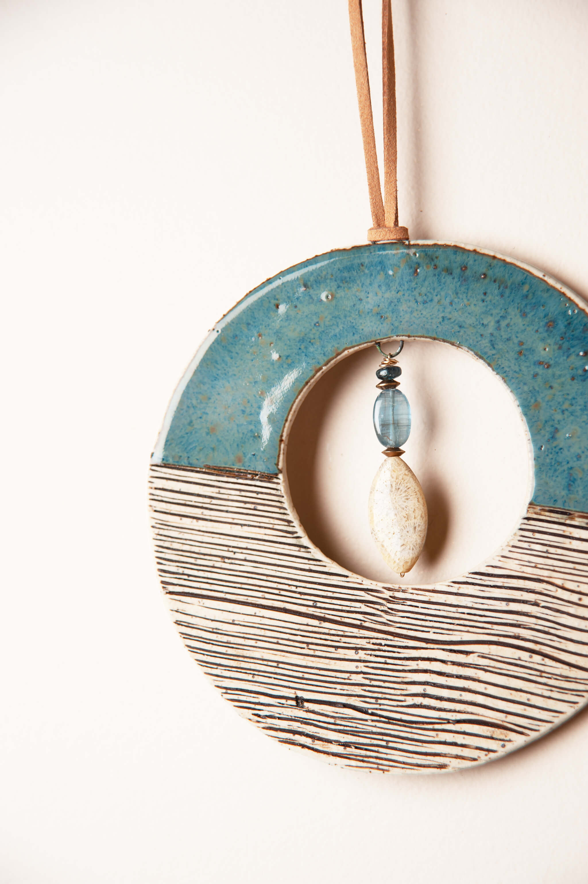 Kyanite and fossilized coral agate on copper chain inside small handmade coastal ceramic wall hanging From the Fire FTF_0726 by Jester Swink