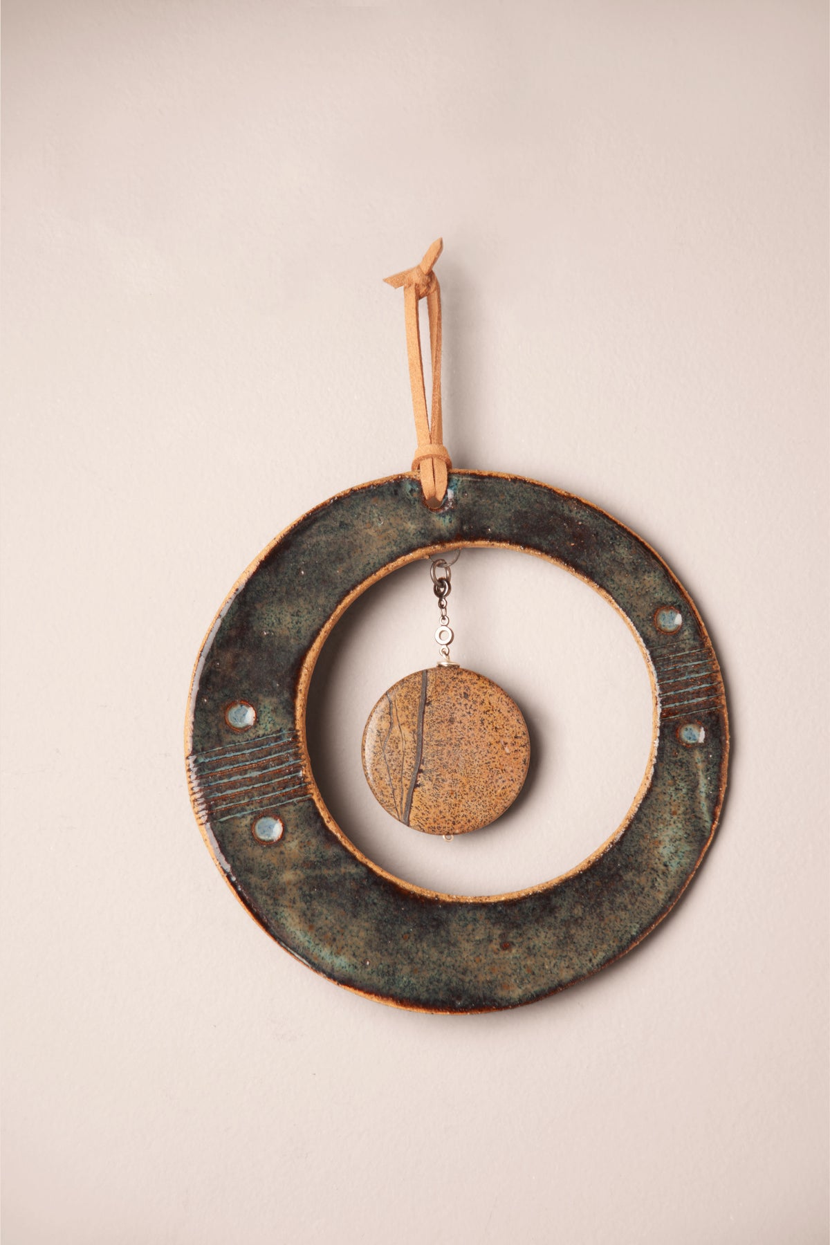 Detail of the picture jasper disc and pressed rim on a small handmade round ceramic wall hanging, kiln fired by Jester Swink, Santa Cruz Mountains California