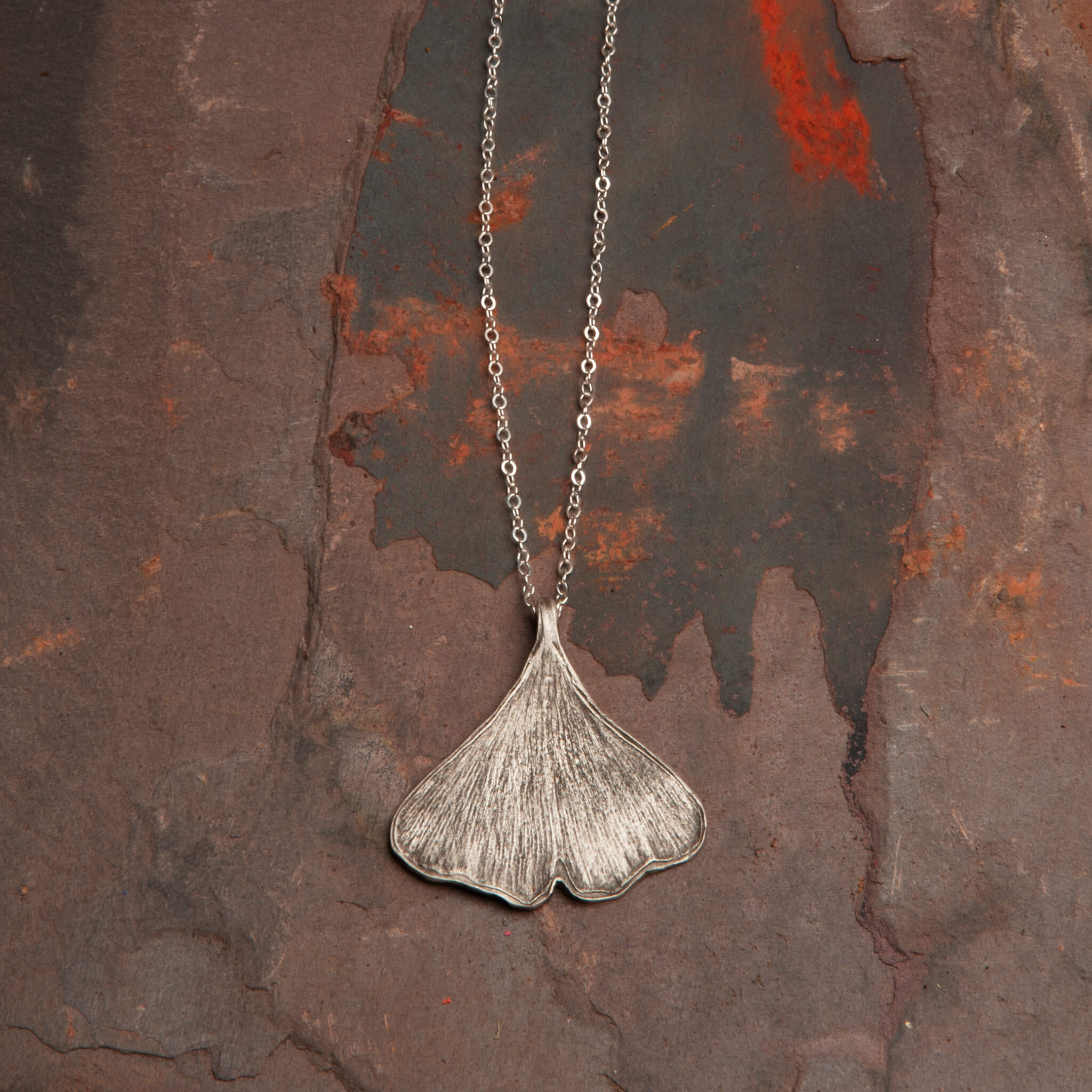 Close-up of sterling silver ginkgo leaf pendant showing organic texture and handcrafted details