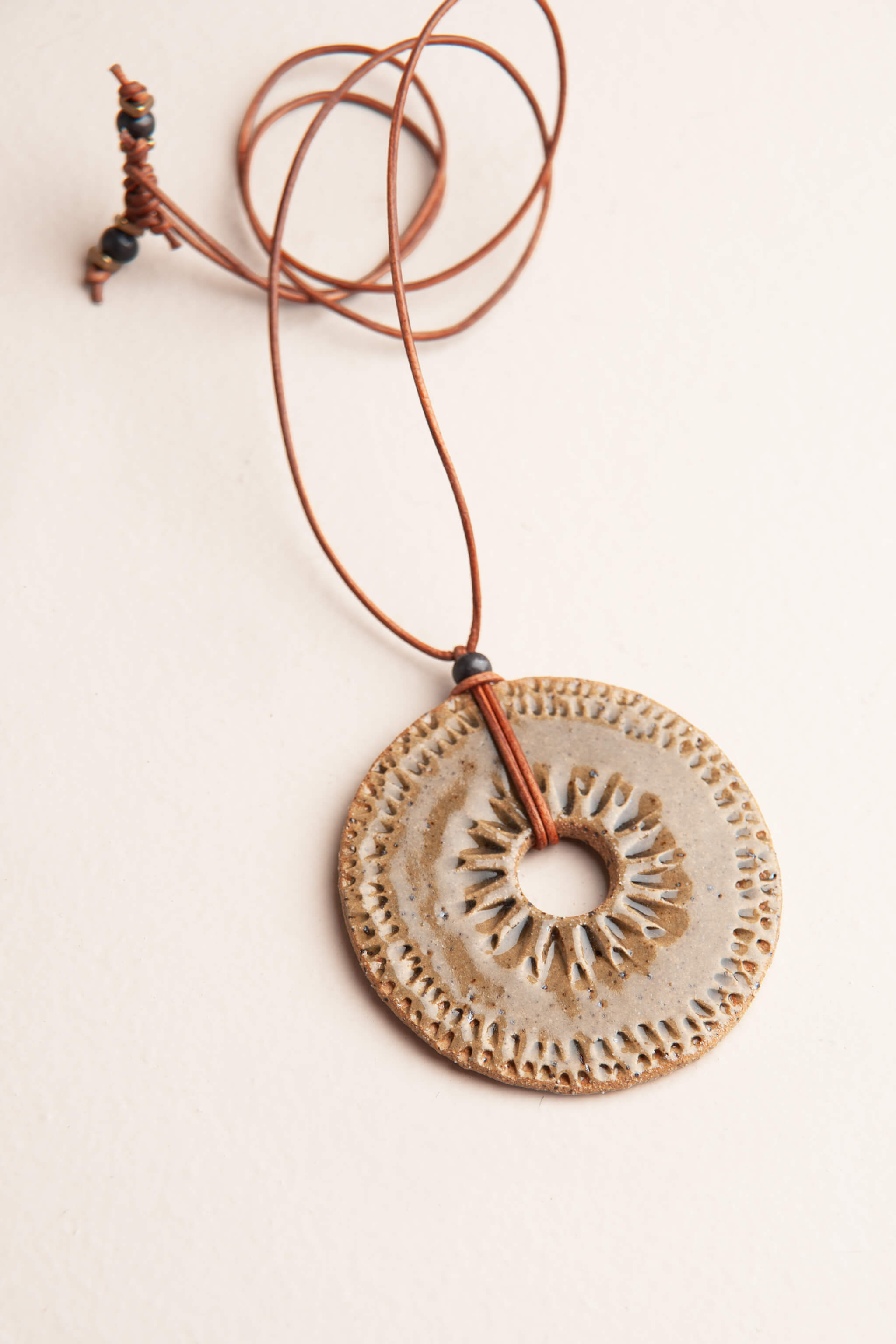 Handmade speckled buff ceramic sun disc pendant necklace in olive grey with hand pressed mountain peak border on caramel Italian leather, kiln fired by Jester Swink Santa Cruz Mountains — From the Fire FTF_0726