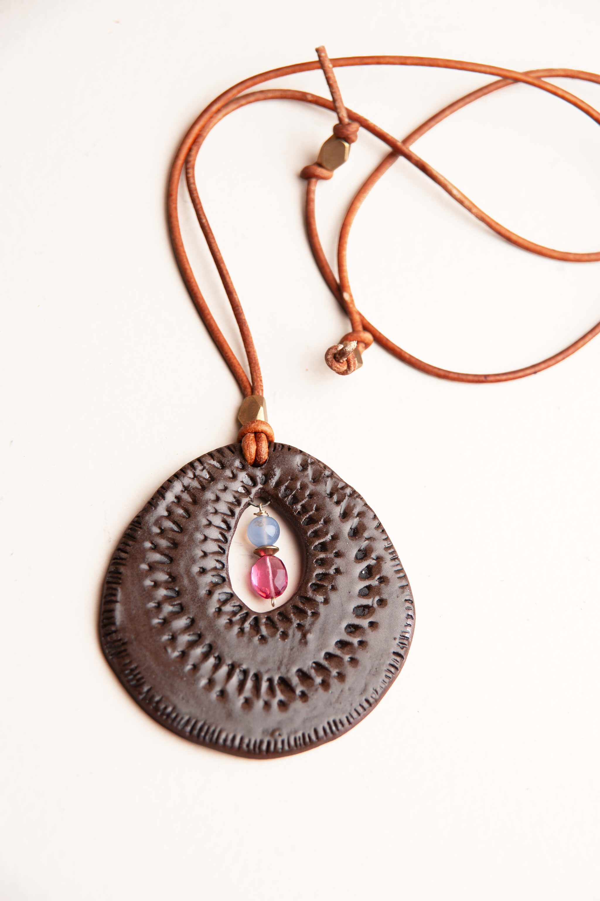 Handmade ceramic sunburst pendant necklace in chocolate brown terracotta with rubelite and chalcedony on adjustable Italian leather, kiln fired by Jester Swink Santa Cruz Mountains — From the Fire FTF_0726