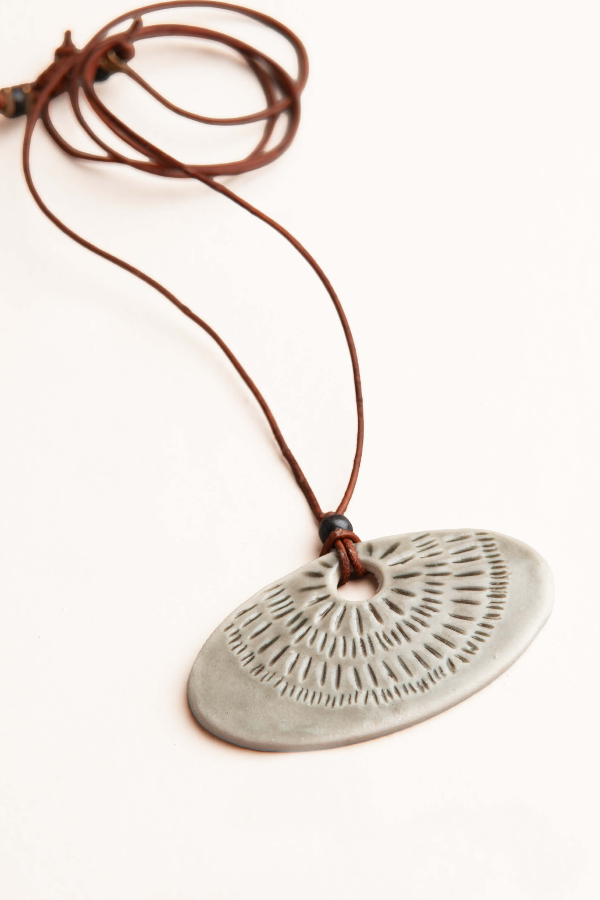 Handmade smoke grey porcelain sunray ceramic pendant necklace with hand carved radiating lines on brown Italian leather, kiln fired by Jester Swink Santa Cruz Mountains — From the Fire FTF_0726