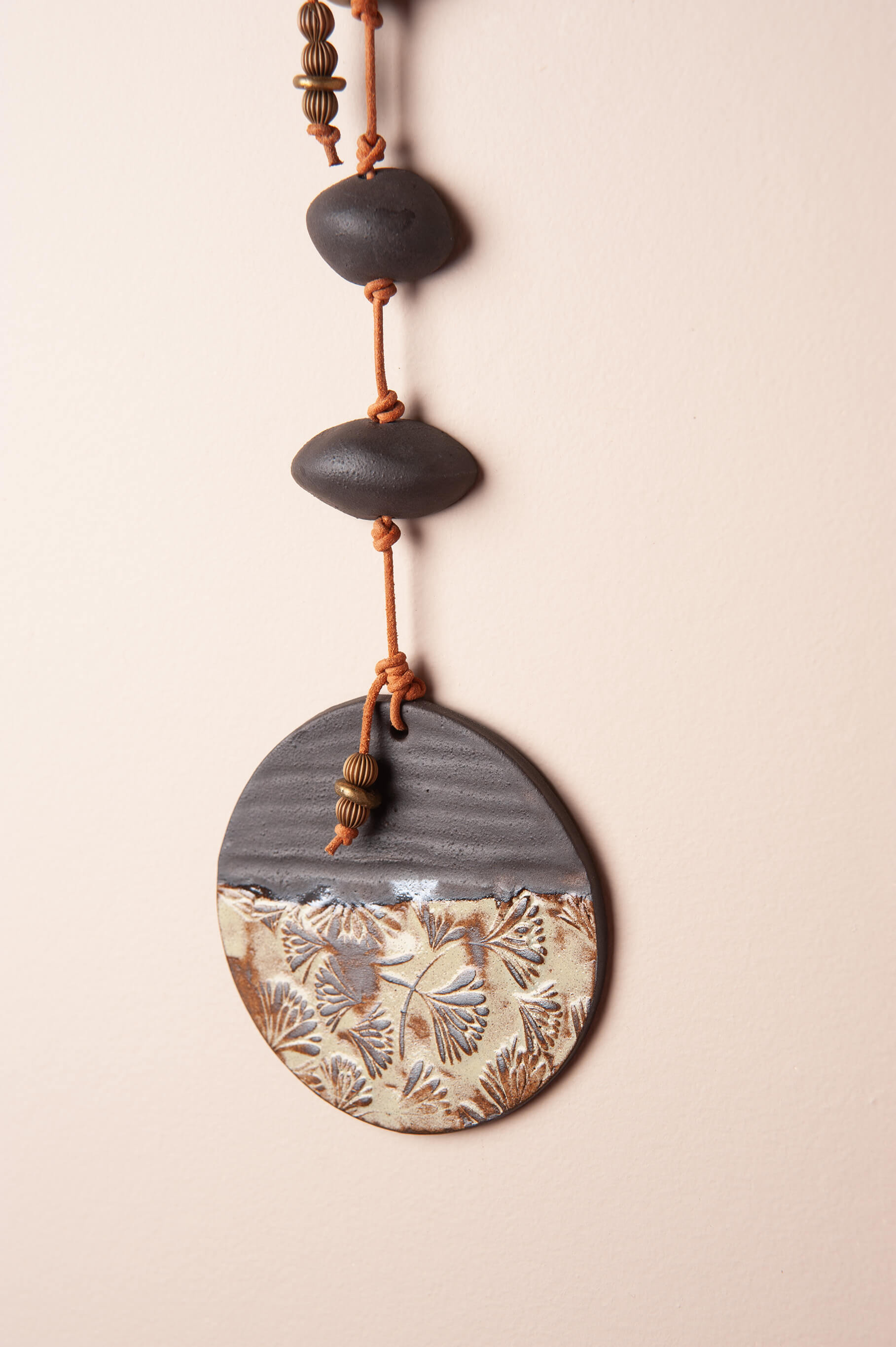 Close-up of Japanese floral impression in dark clay with sage glaze — handmade ceramic wall art by Jester Swink Santa Cruz Mountains