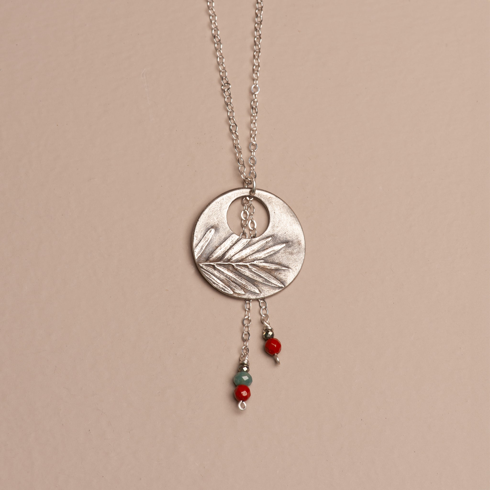 Oxidized sterling silver crescent moon pendant with redwood leaf texture and cascading drops of red jasper, blue apatite, and metallic pyrite.