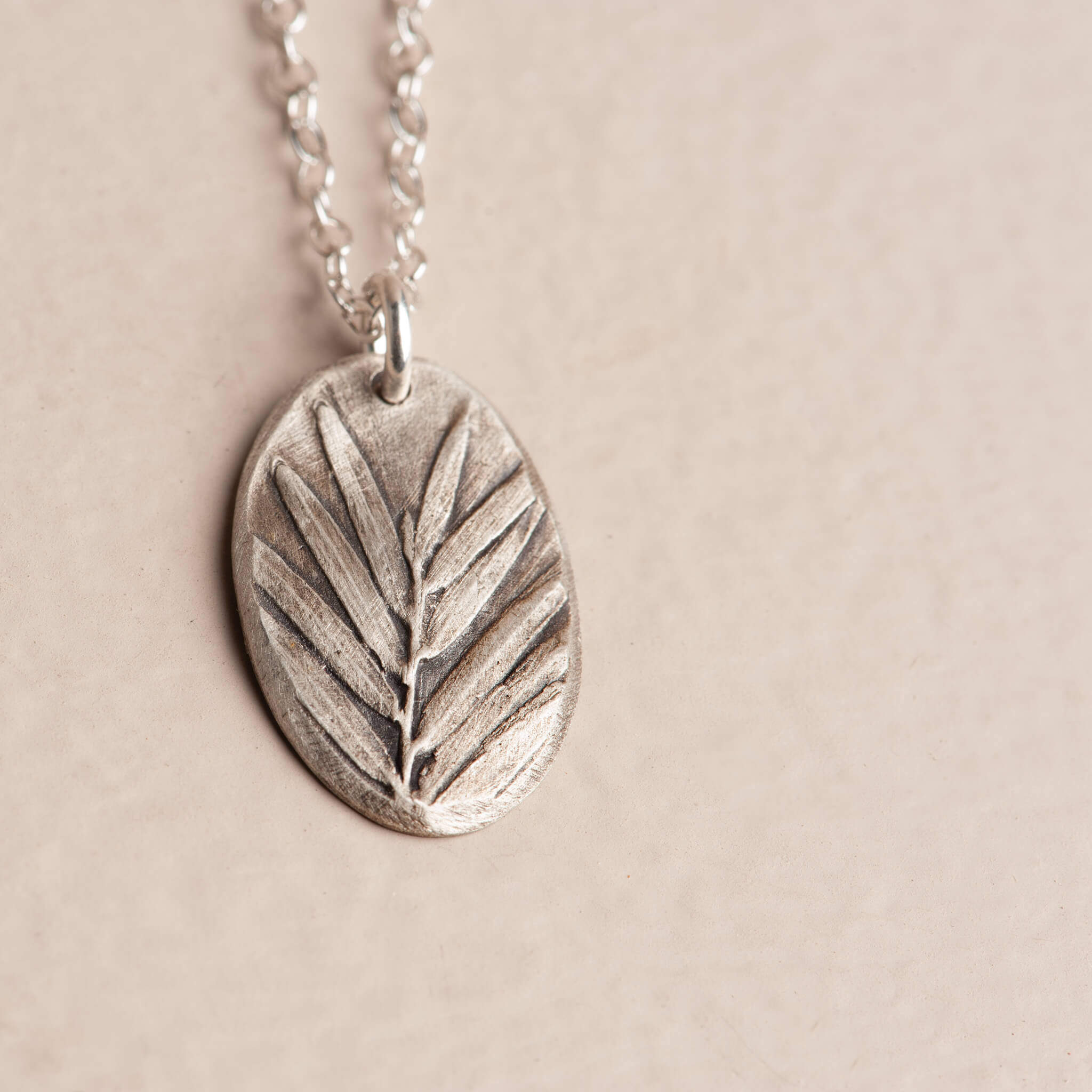 Close-up artisan sterling silver botanical impression pendant necklace, handcrafted redwood jewelry, Jester Swink Santa Cruz Mountains