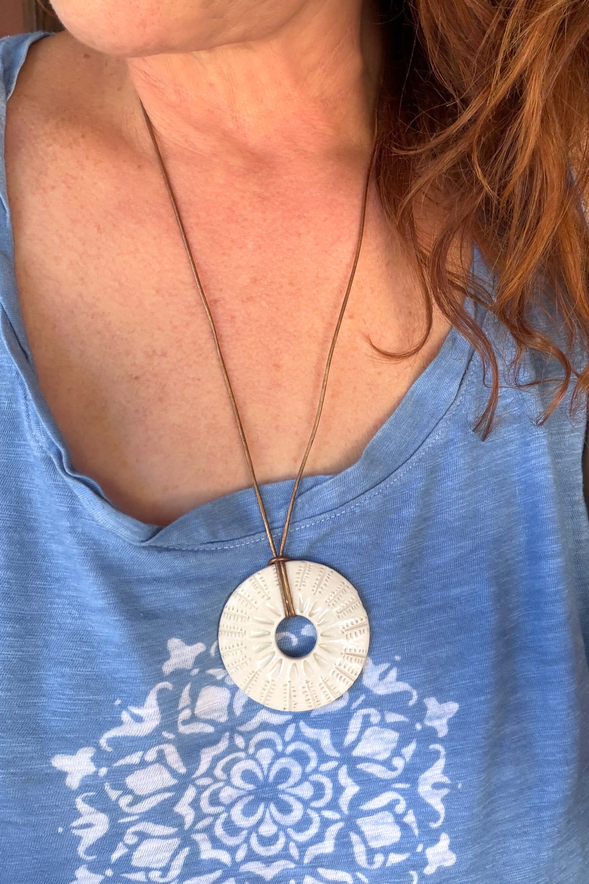 Handmade white ceramic botanical sunburst pendant necklace worn at long boho length on gold metallic leather — From the Fire FTF_0726 by Jester Swink