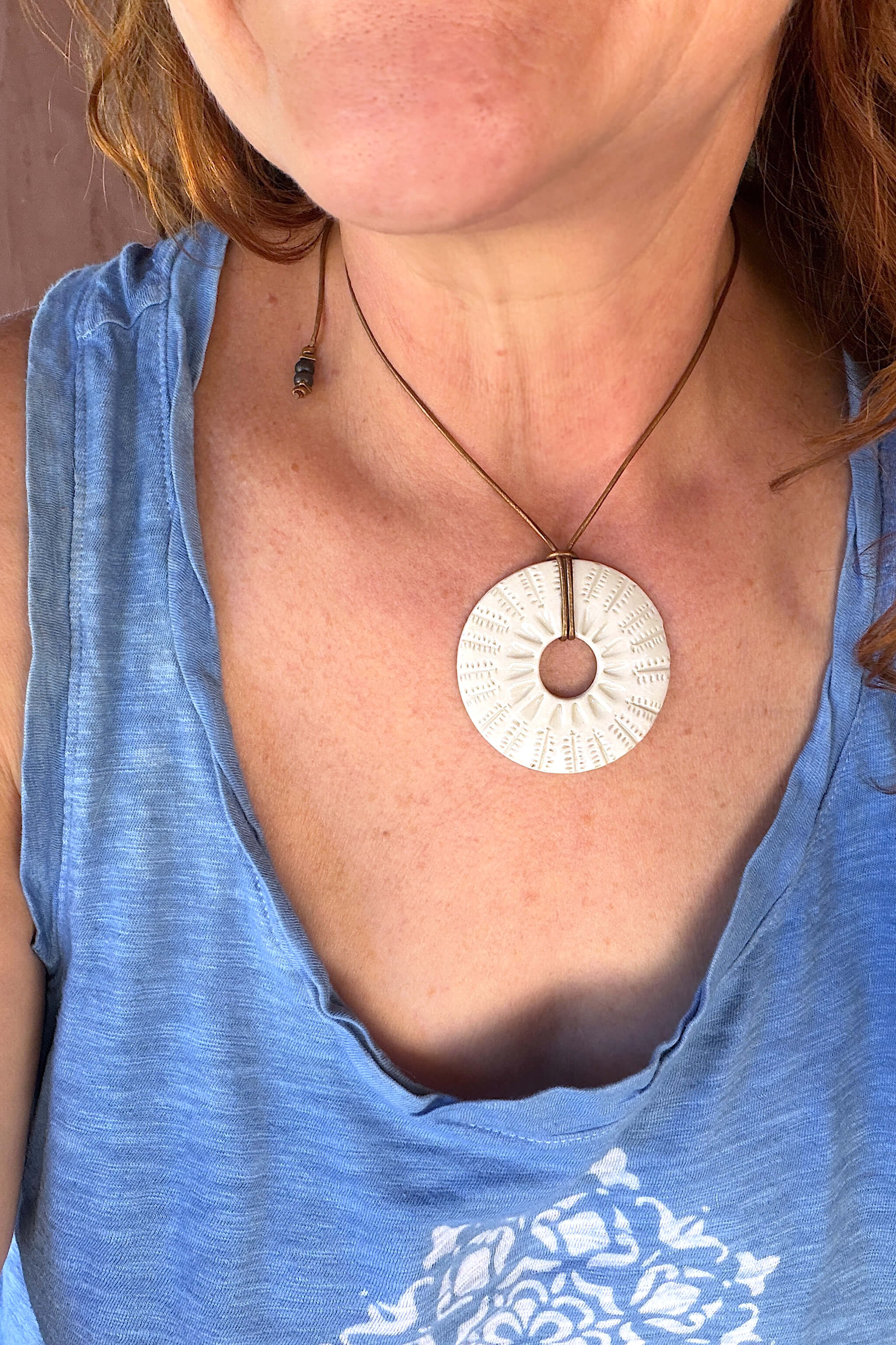 Handmade white ceramic botanical sunburst pendant necklace worn at shorter length — botanical ceramic jewelry From the Fire FTF_0726 by Jester Swink