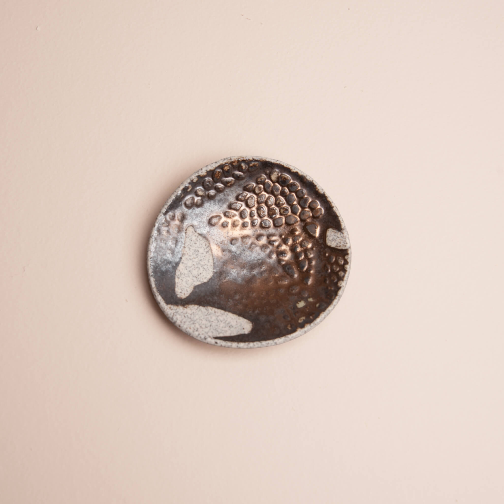 Overhead view of handmade ceramic Copper Seed Pod ring dish with metallic bronze glaze and raised seed pod texture on dragon fruit clay, by Jester Swink