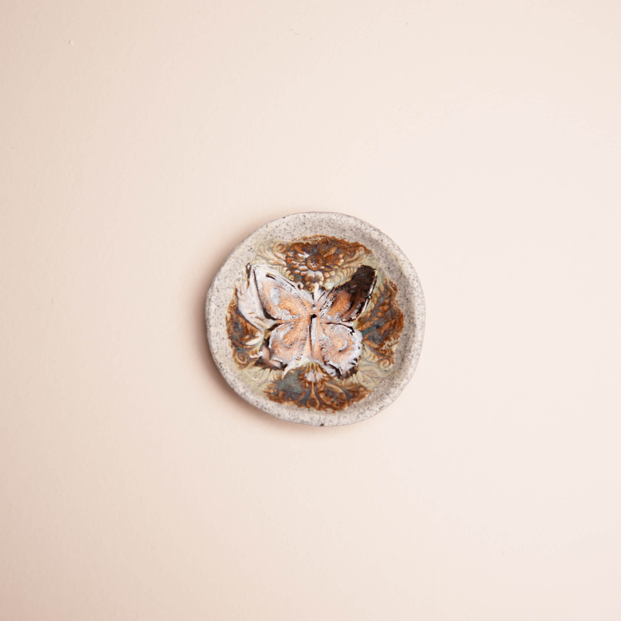 Overhead view of handmade ceramic Copper Butterfly ring dish showing butterfly and floral scroll texture, copper and blue tigers eye glaze on dragon fruit clay, by Jester Swink