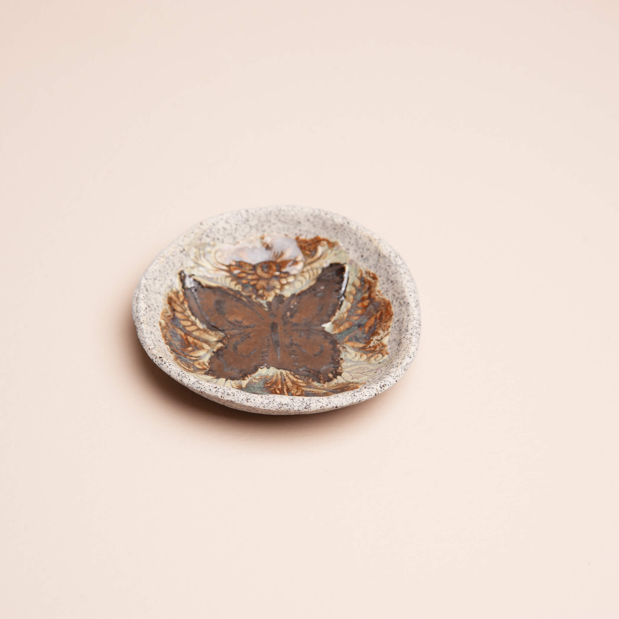 Angled view of handmade ceramic Copper Butterfly ring dish with copper metallic glaze and blue tigers eye surround on dragon fruit clay, by Jester Swink