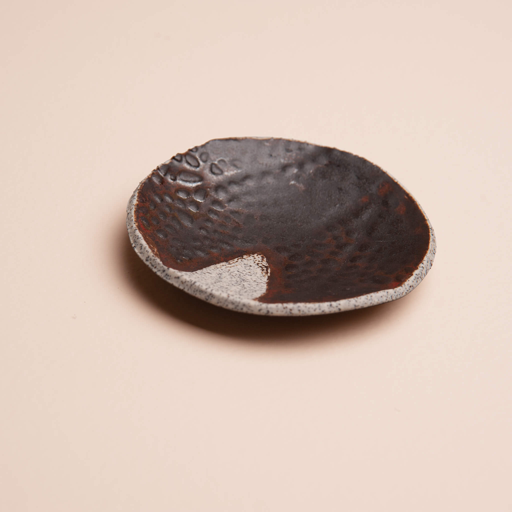 Angled view of handmade ceramic Earth Seed Pod ring dish showing depth and organic shape, deep earthy brown glaze on dragon fruit clay, by Jester Swink