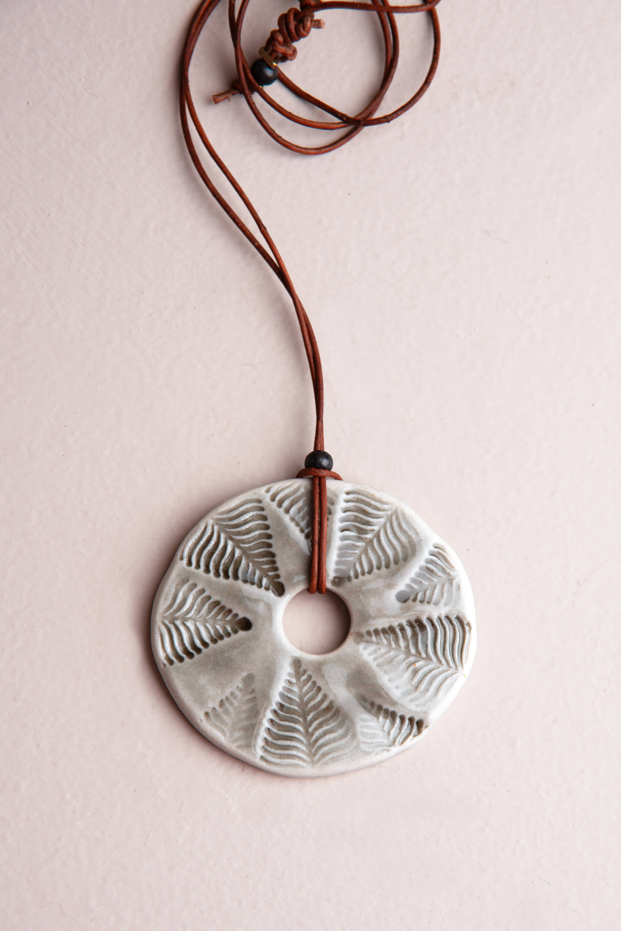 Handmade smoke grey porcelain fern impression ceramic pendant necklace on reddish brown Italian leather, kiln fired by Jester Swink Santa Cruz Mountains — From the Fire FTF_0726