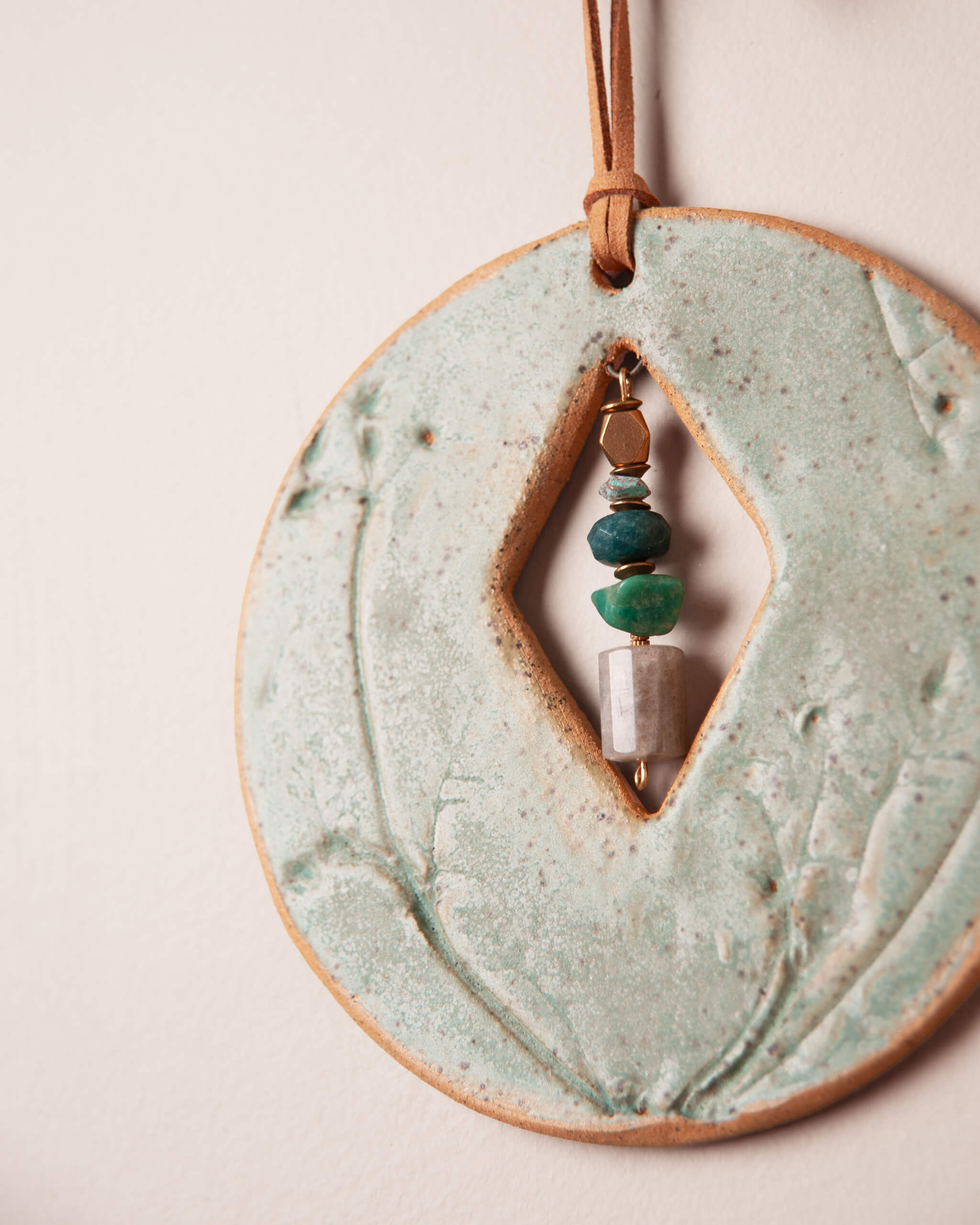 Close up of balanced stone stack inside diamond opening showing labradorite, green onyx and amazonite separated by bronze spacer beads and patinated brass accents