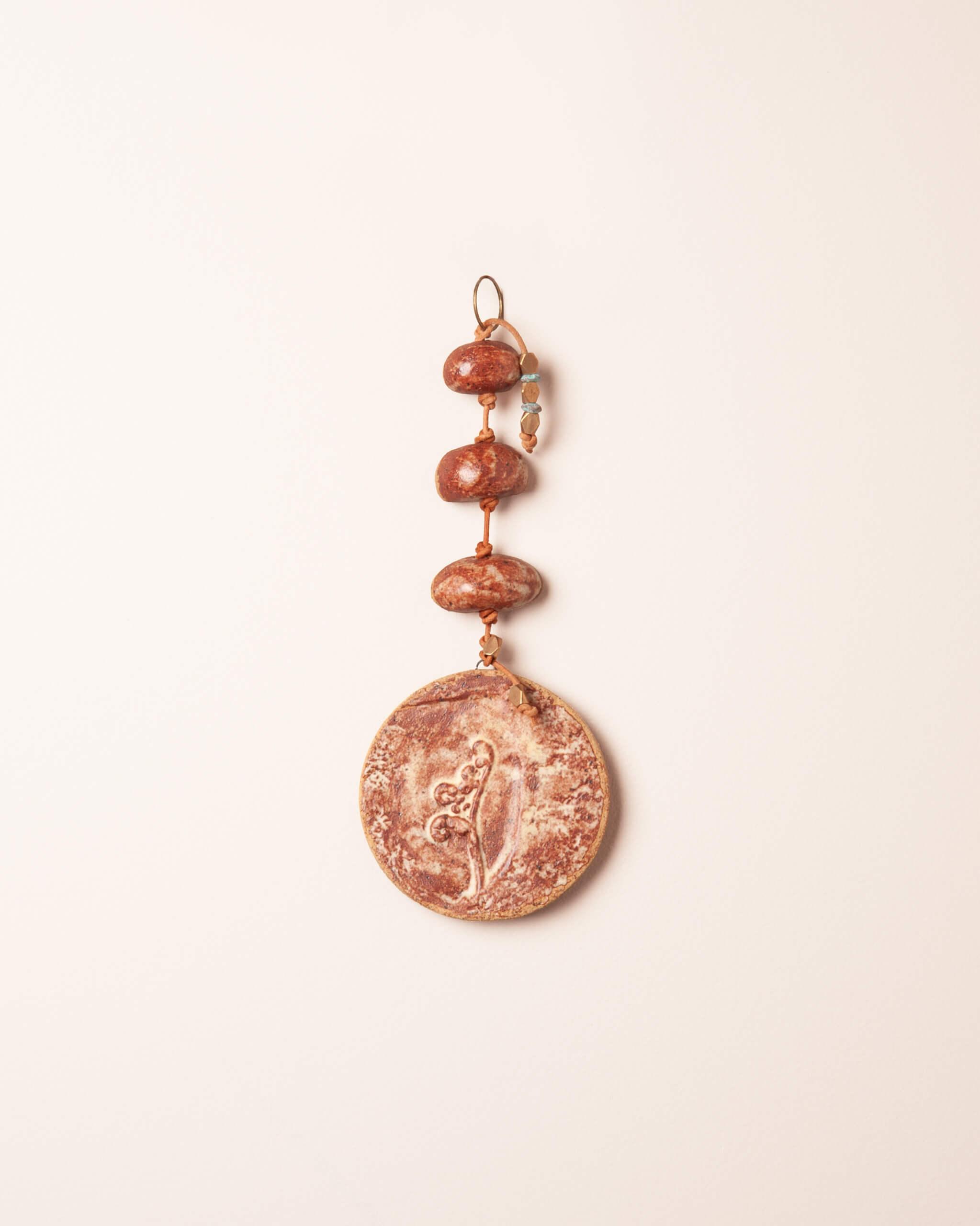 Fiddlehead Stack handmade ceramic wall hanging with river rock forms, raised fiddlehead fern impression and terracotta cream glaze, made in the Santa Cruz Mountains of California