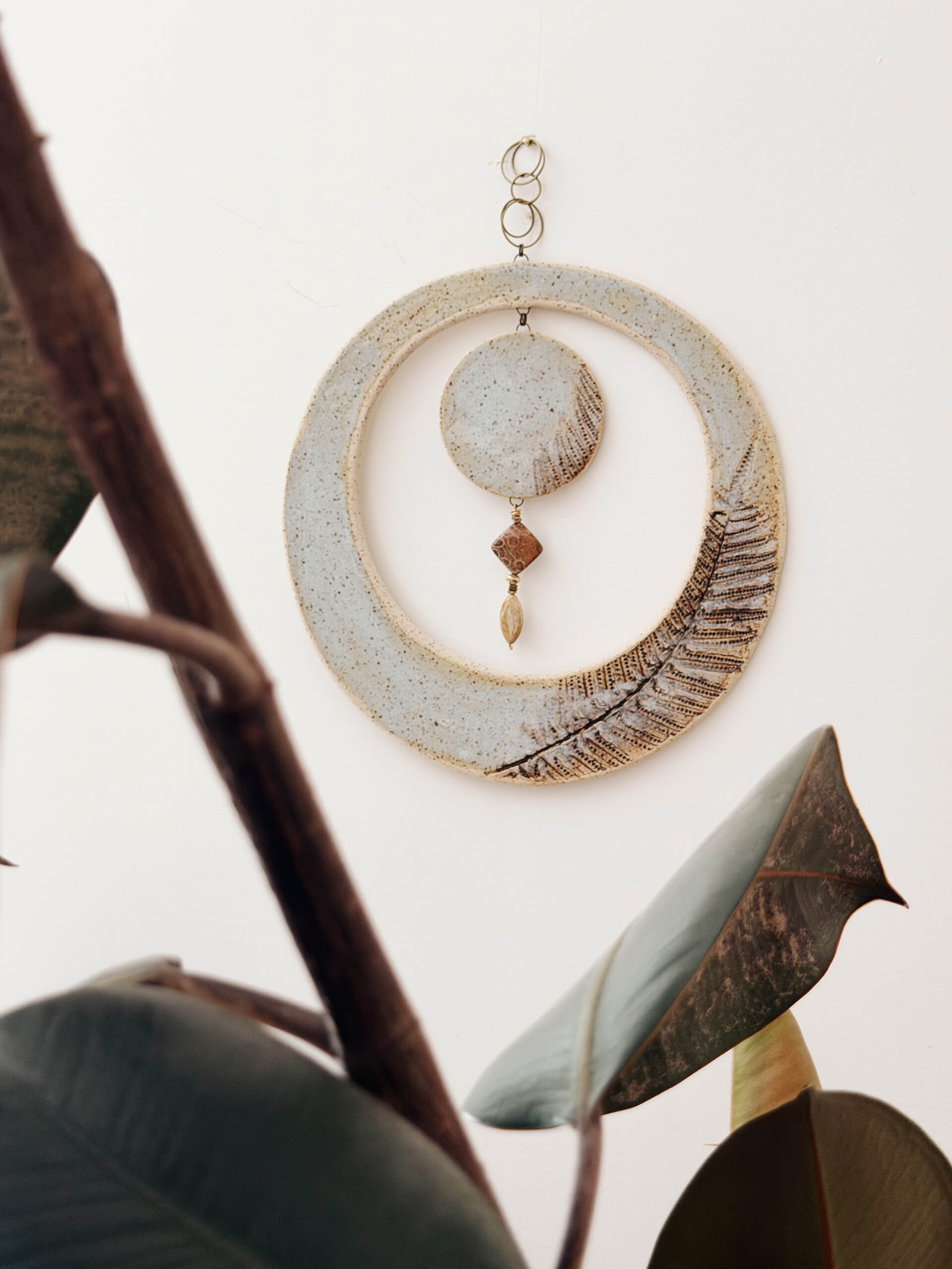 Lunar Fern large ceramic wall hanging displayed on blush wall with rubber plant botanical framing
